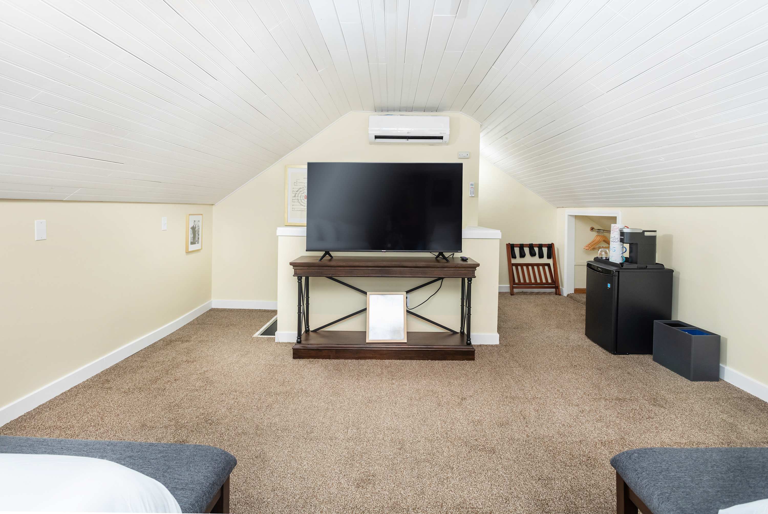 Cozy attic space with a large flat-screen TV and compact refreshment area.