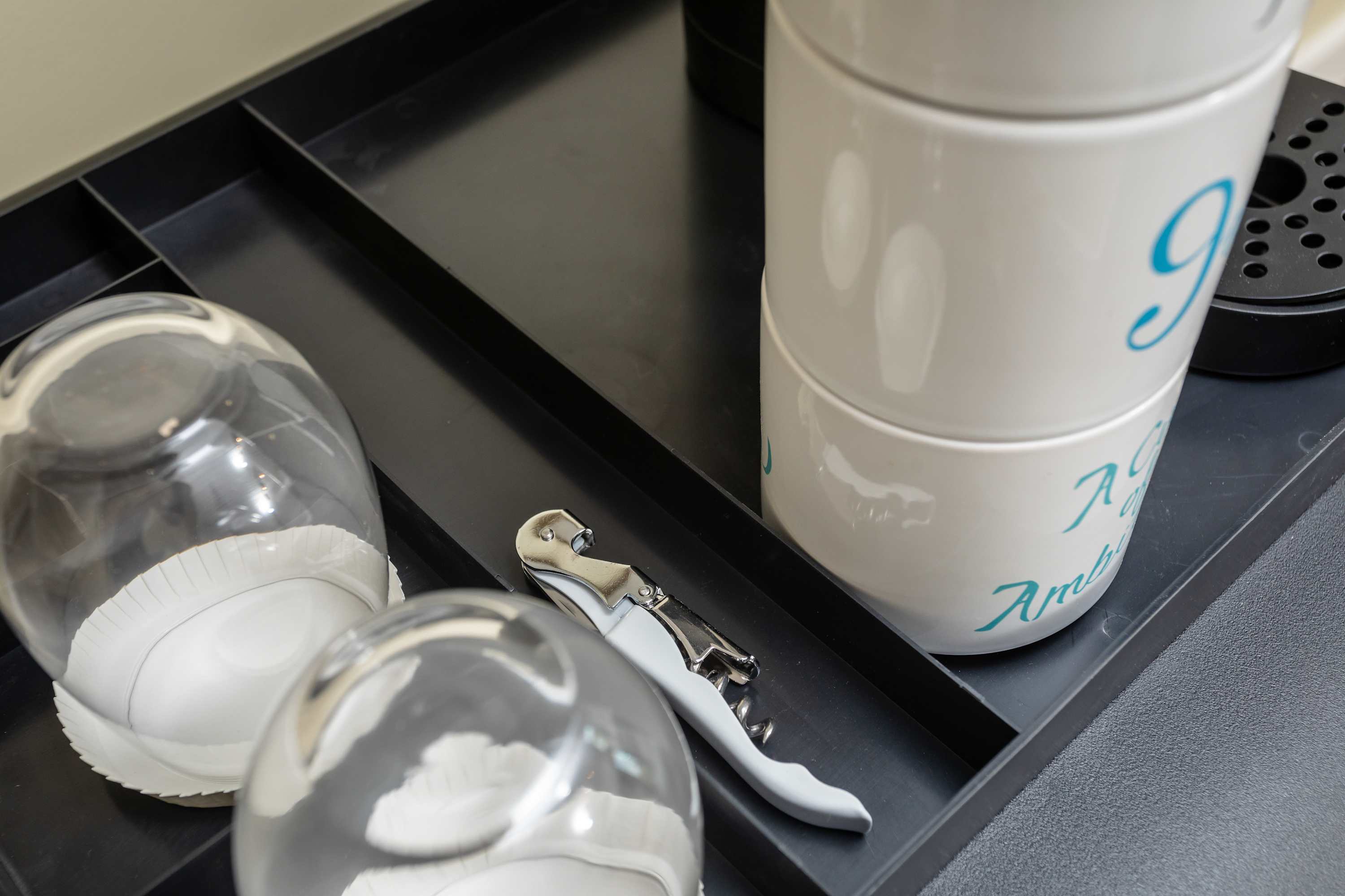Organized tray with glassware, mugs, and a corkscrew for convenient beverage preparation.