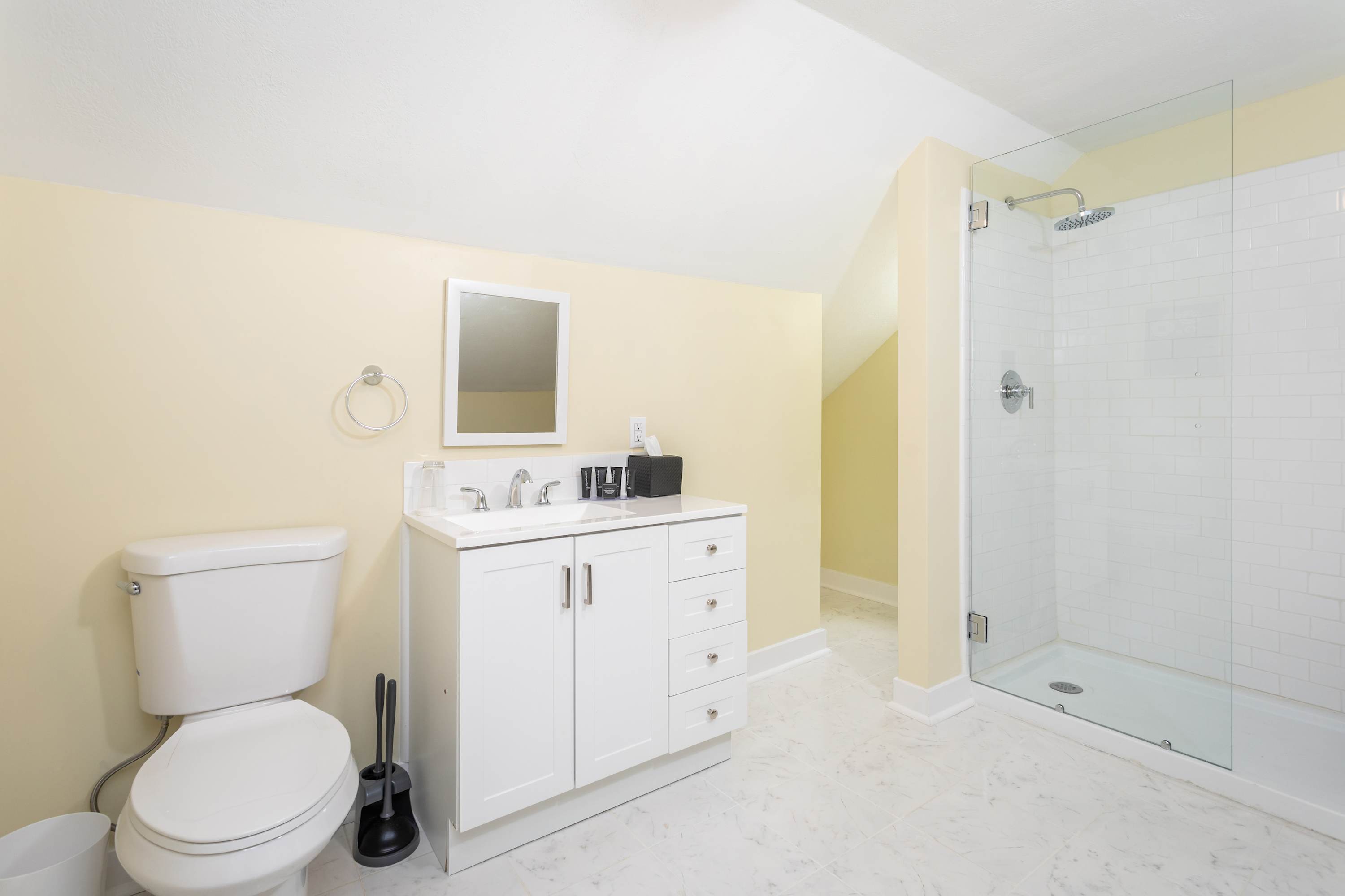 Modern bathroom with a glass-enclosed shower and white vanity under a sloped ceiling