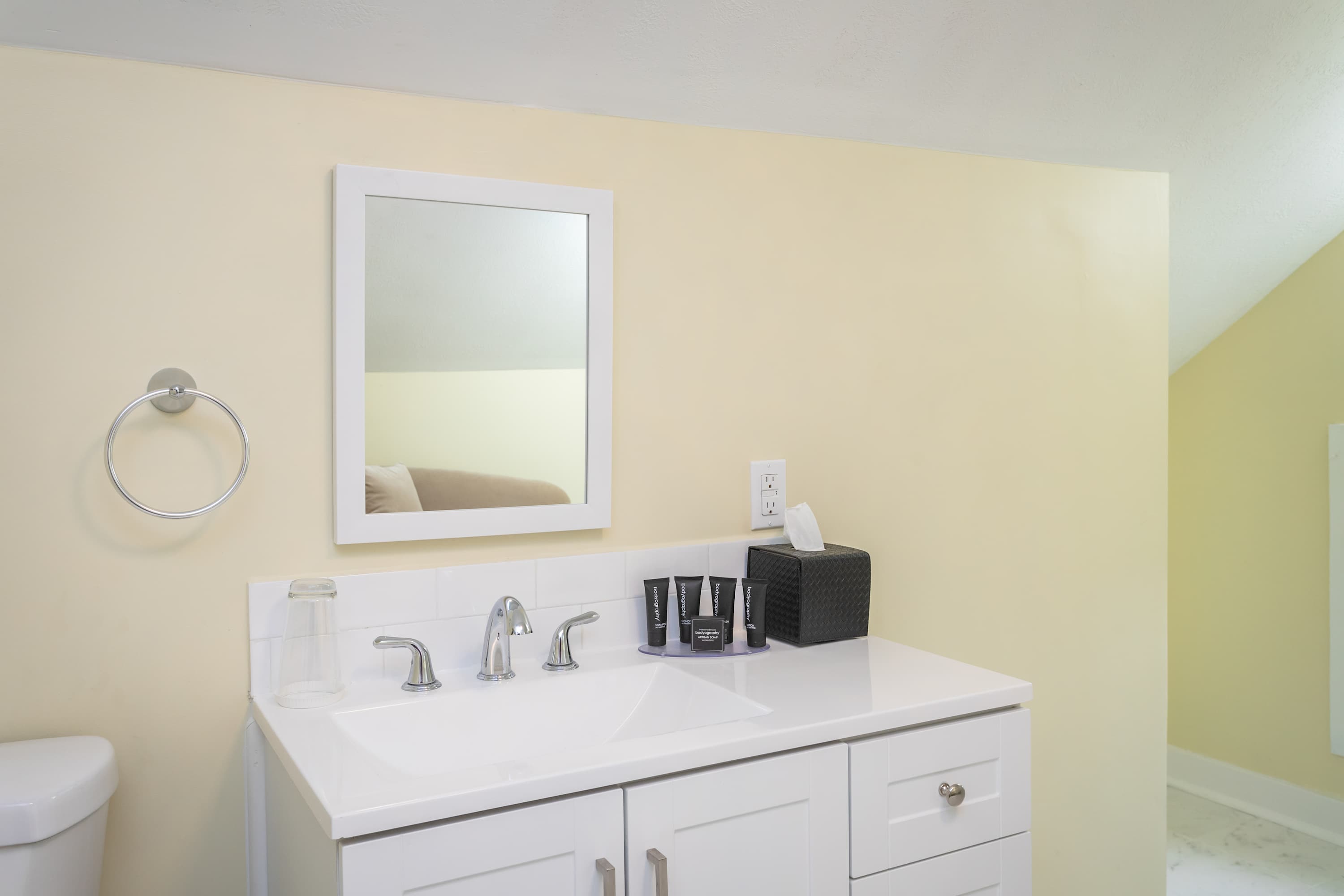 Modern bathroom vanity with a white framed mirror and essential toiletries.