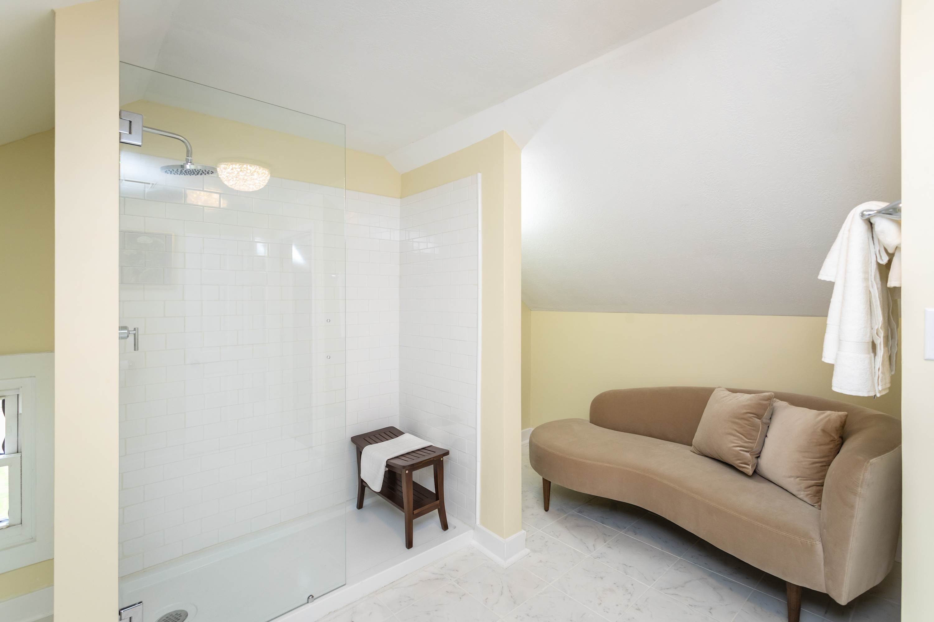Relax in the cozy seating area adjacent to the spacious walk-in shower with white subway tiles.