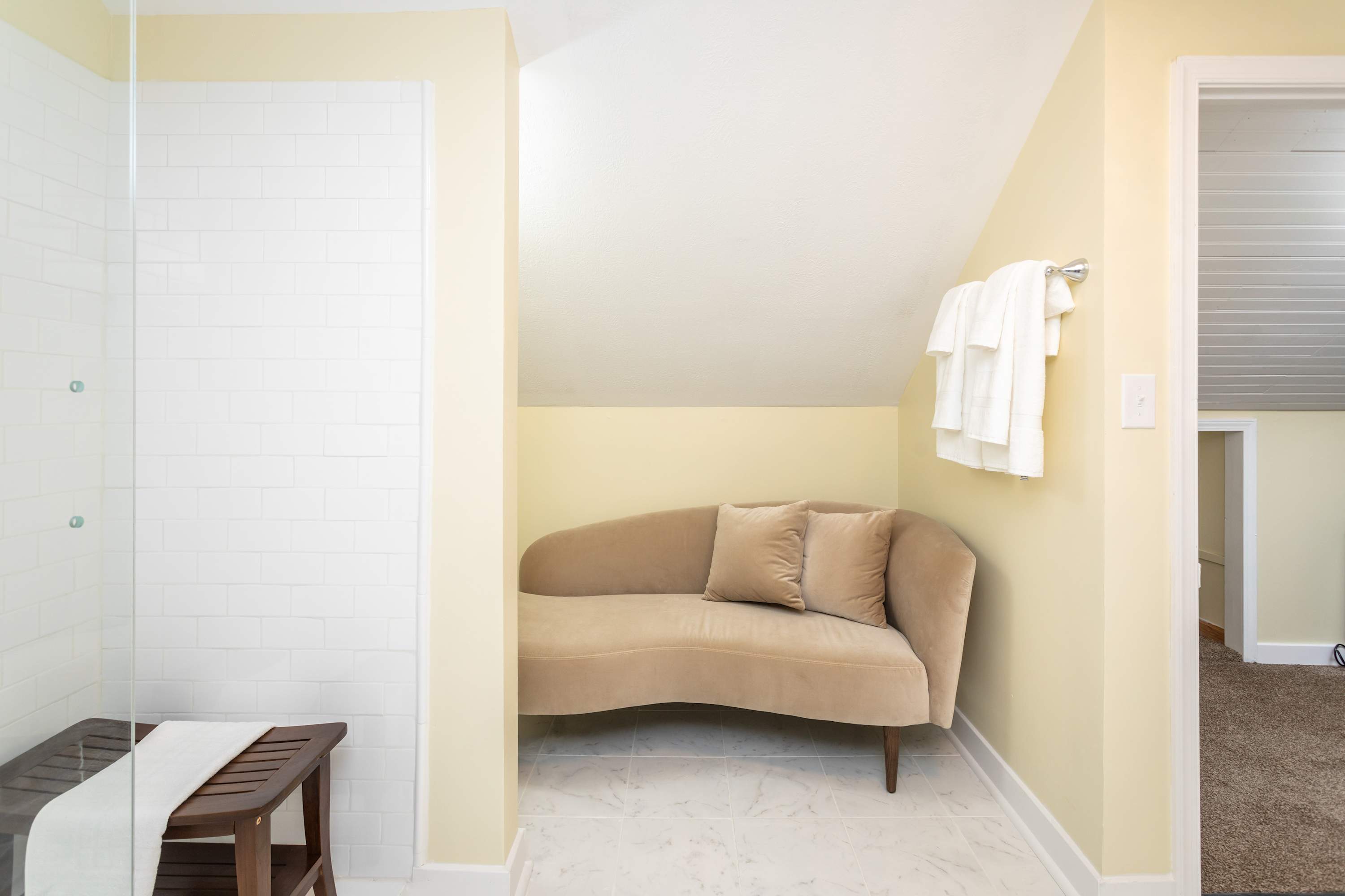 Cozy seating area with soft cushions adjacent to a tiled shower space.