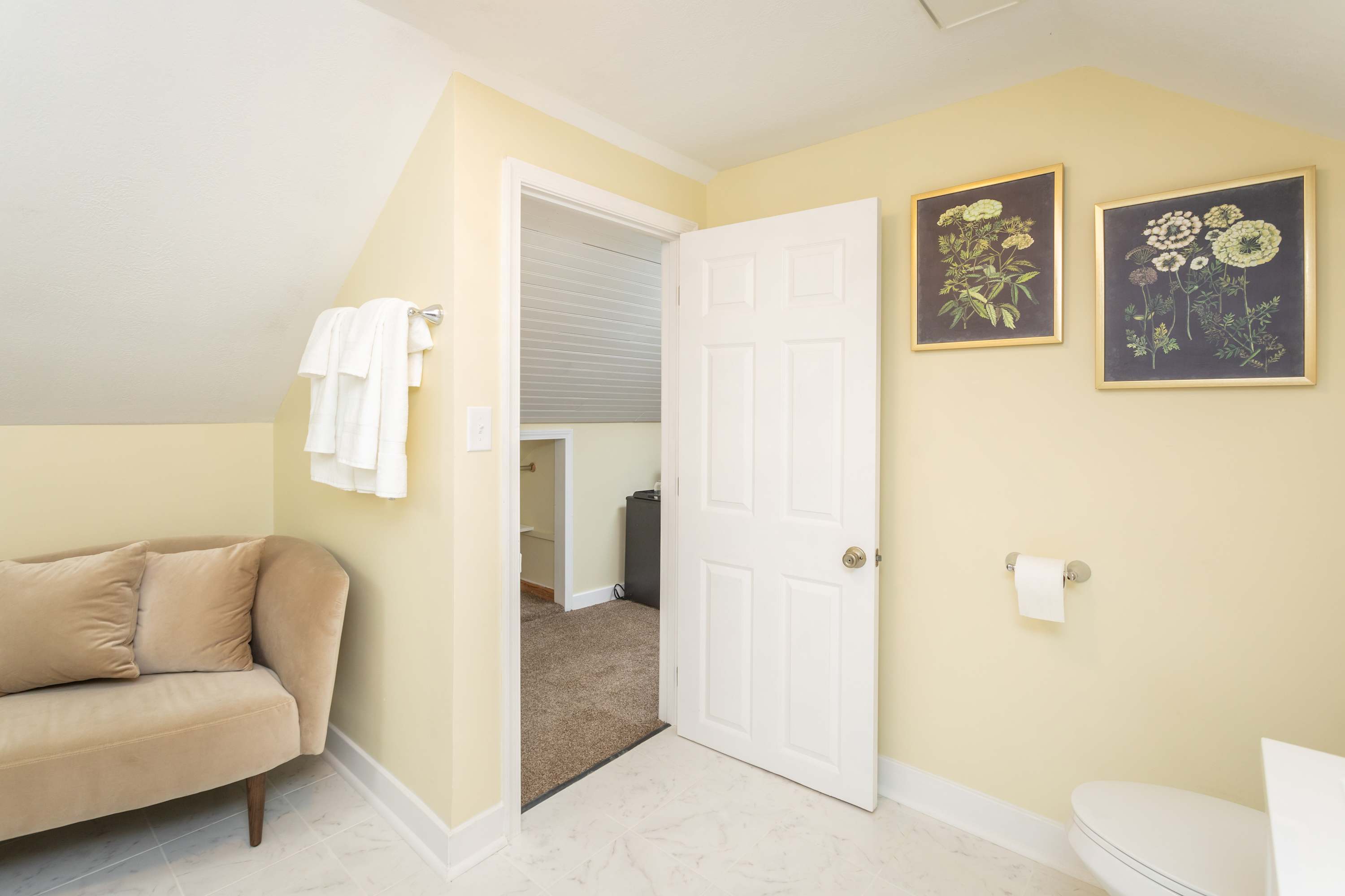 Soft beige sofa and floral artwork add warmth to this bathroom space.