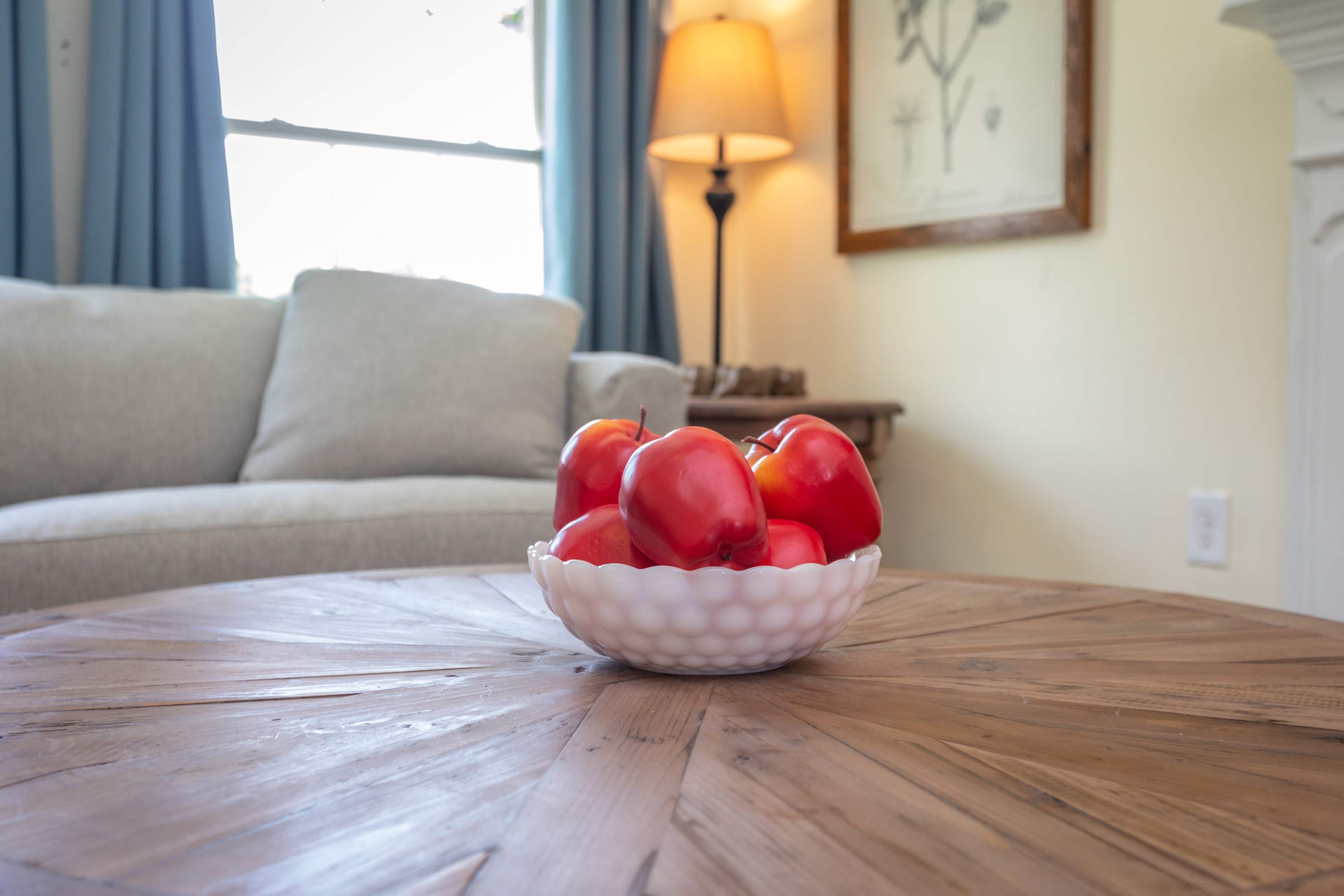 A cozy living room with a wooden coffee table and decorative bowl of red apples.