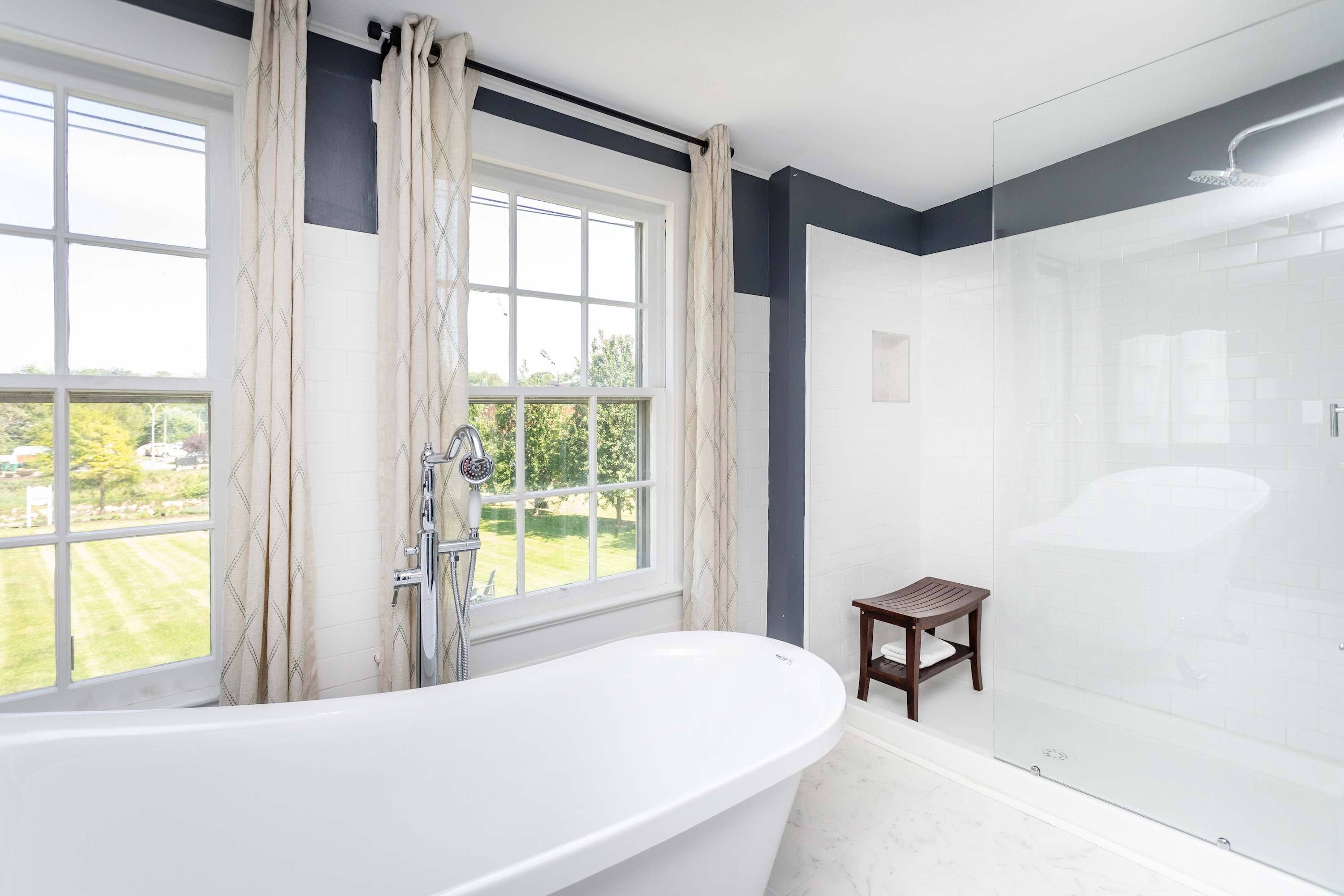 Modern bathroom featuring a freestanding tub and a walk-in glass shower with a wooden bench.