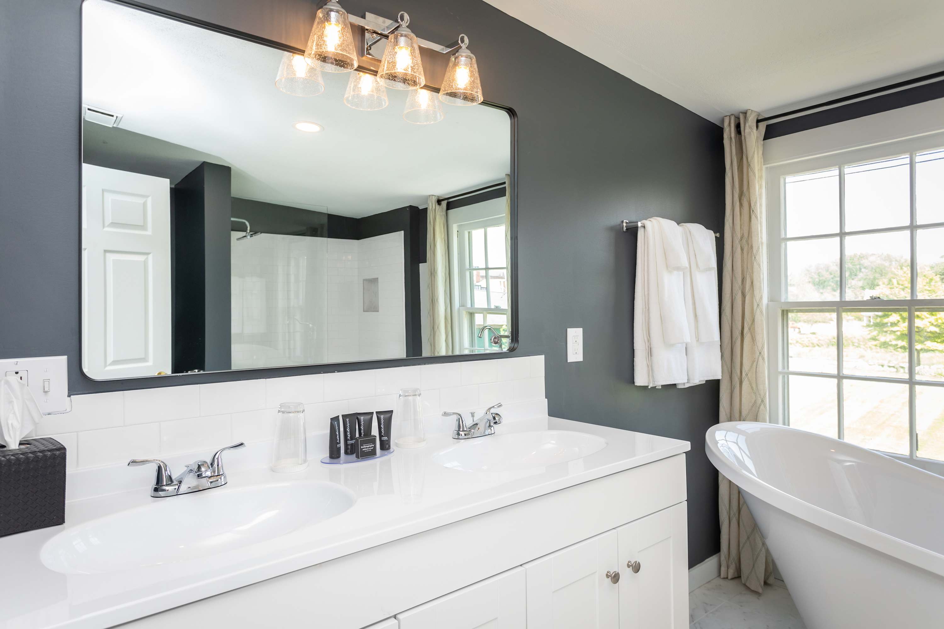 Modern bathroom with a double vanity and freestanding tub by a large window