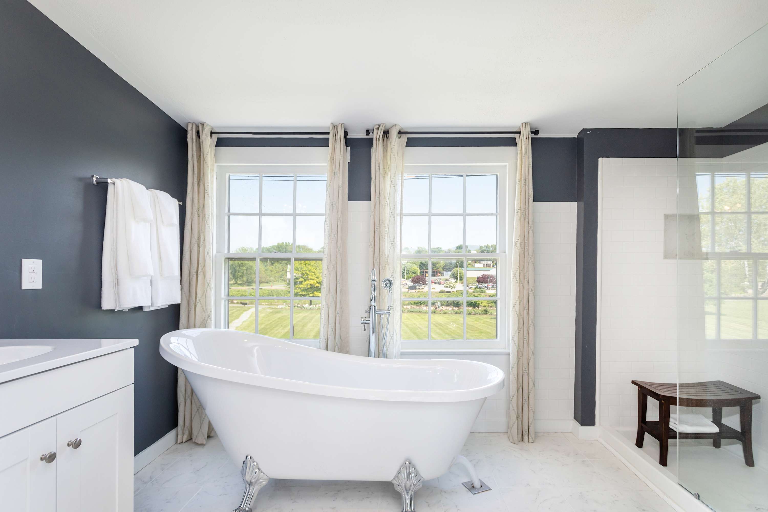 Modern bathroom featuring a freestanding clawfoot tub with natural light from large windows.