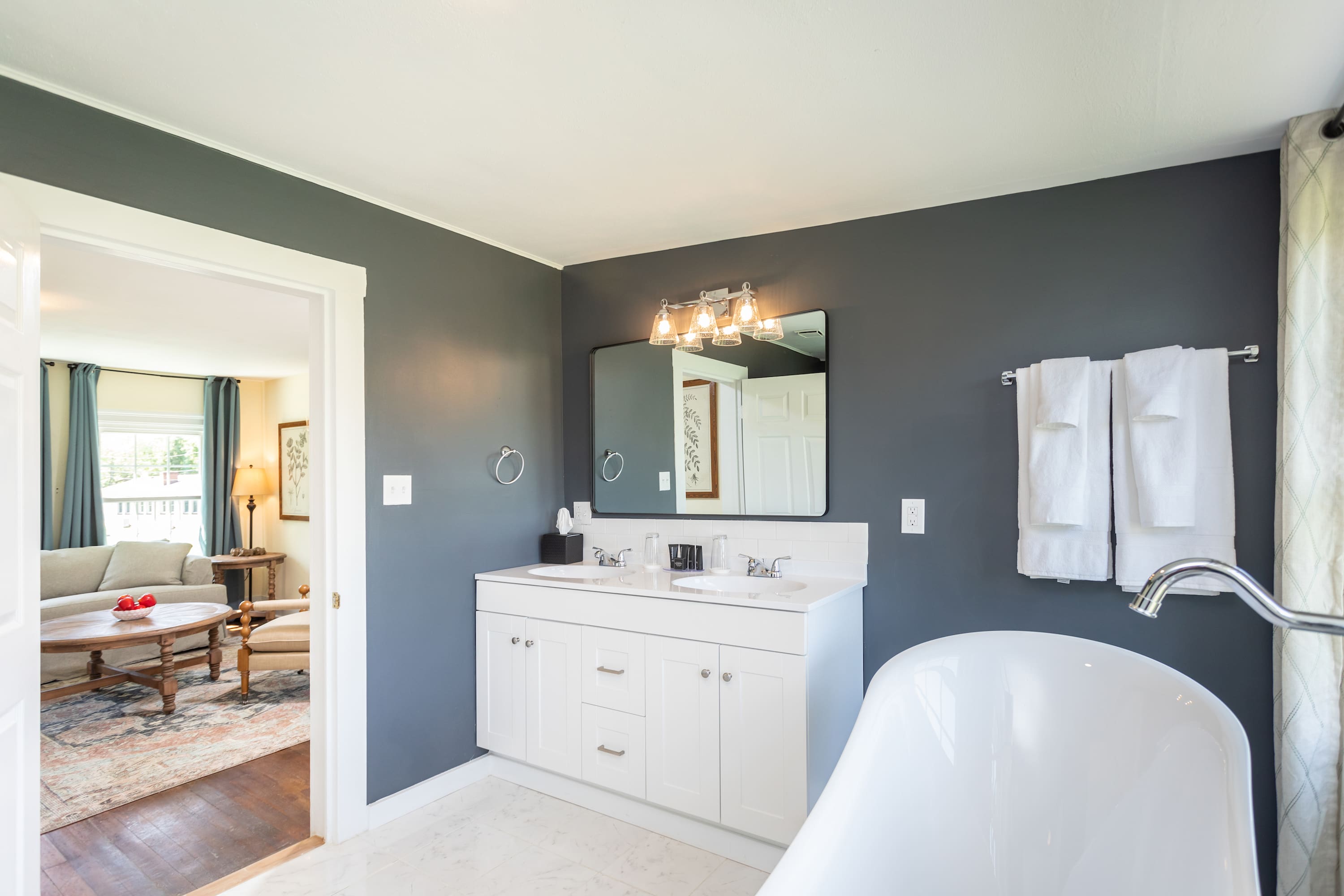 Modern bathroom with a double vanity and freestanding tub adjacent to the living area.