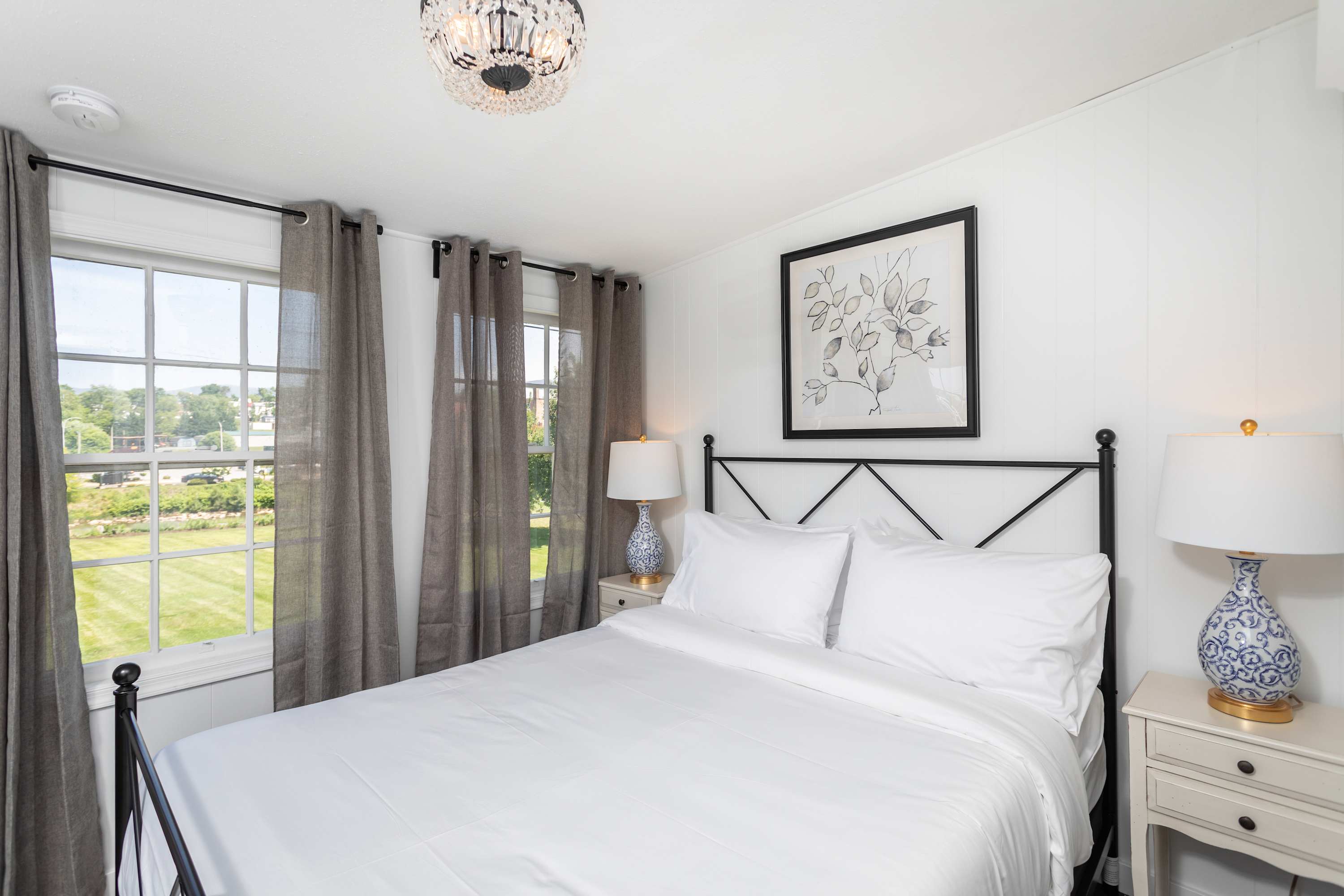 Bright bedroom with large windows and elegant bedside lamps