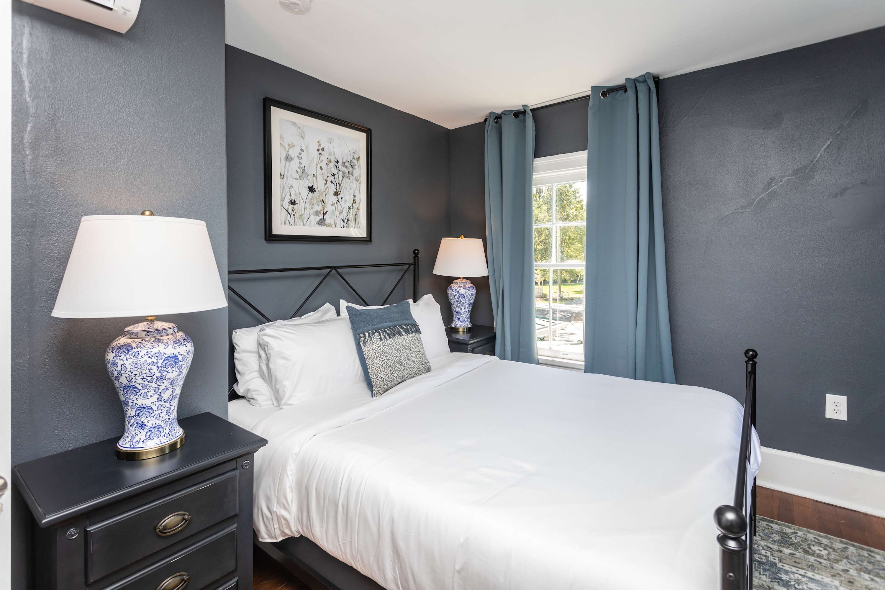 Cozy bedroom with dark walls, blue curtains, and decorative lamps for a relaxing stay.