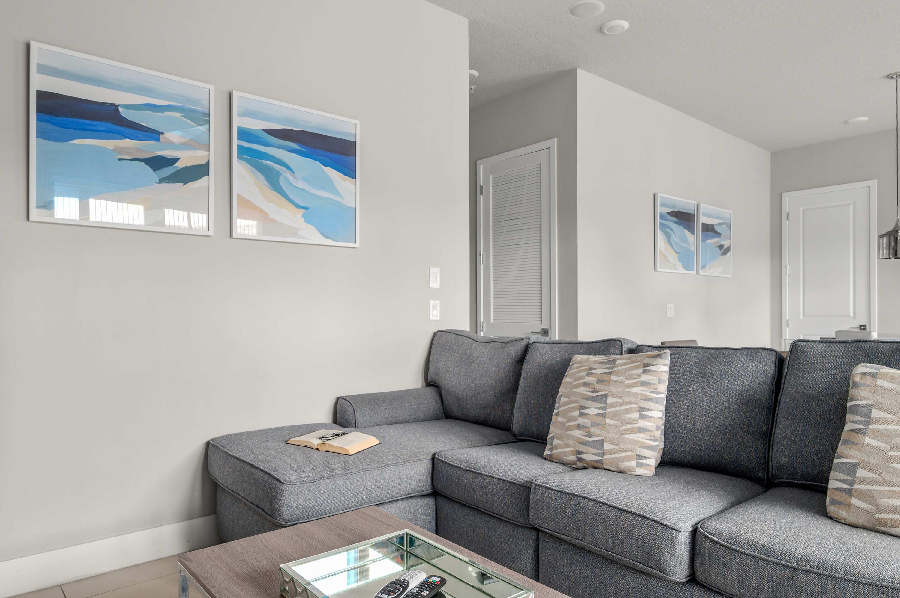 Modern living room with a gray sectional sofa and coastal artwork on the wall