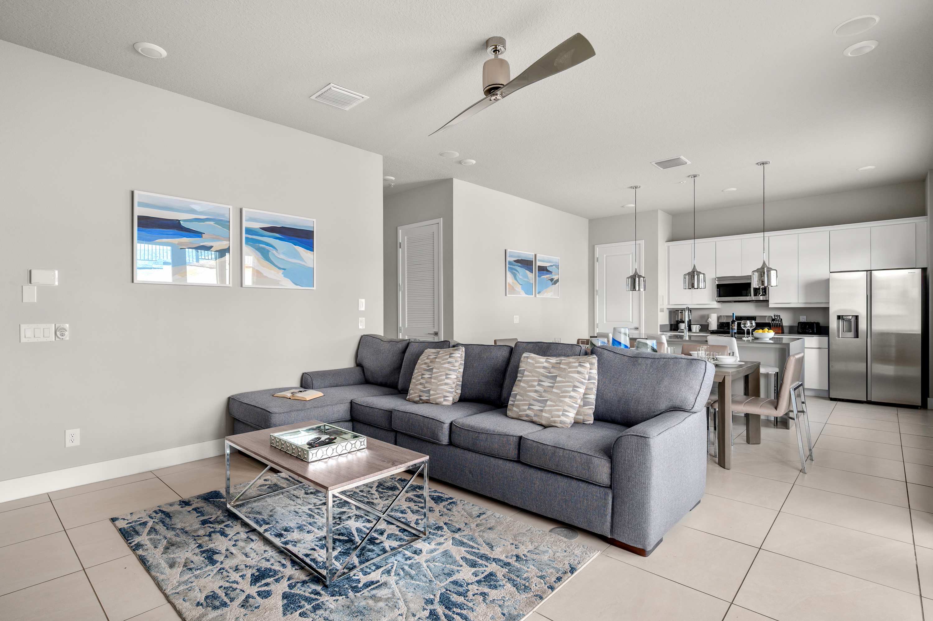 Modern open living area with a gray sectional sofa and a fully equipped kitchen.