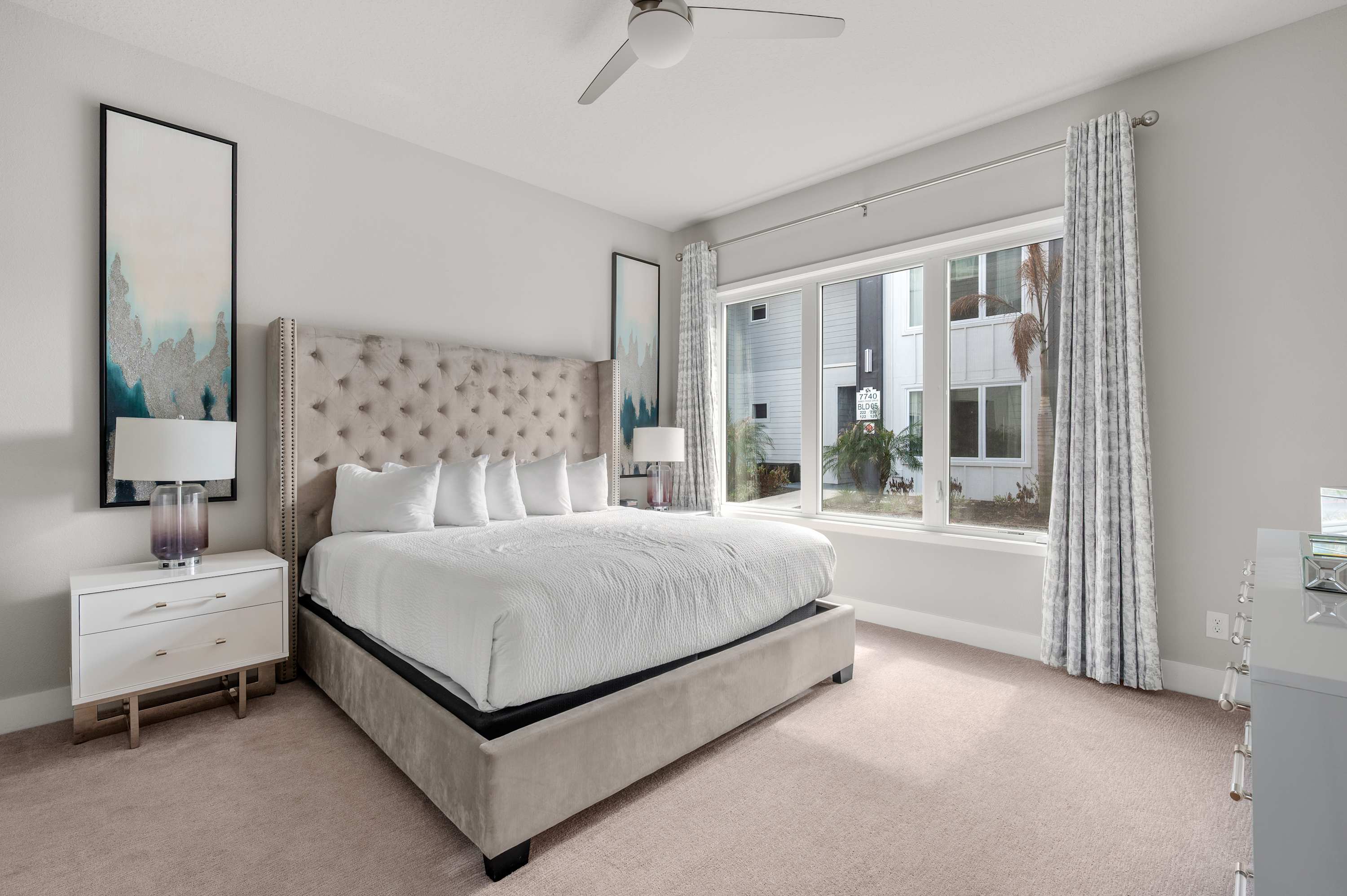 Bright bedroom with a tufted bed and large window offering natural light