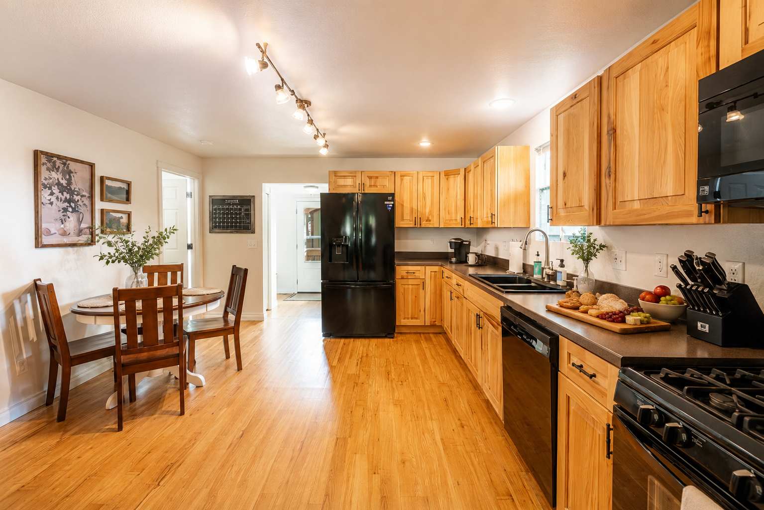 Bright kitchen at The Maple with hickory cabinets, gas range, and full-size fridge — Sheridan, Wyoming