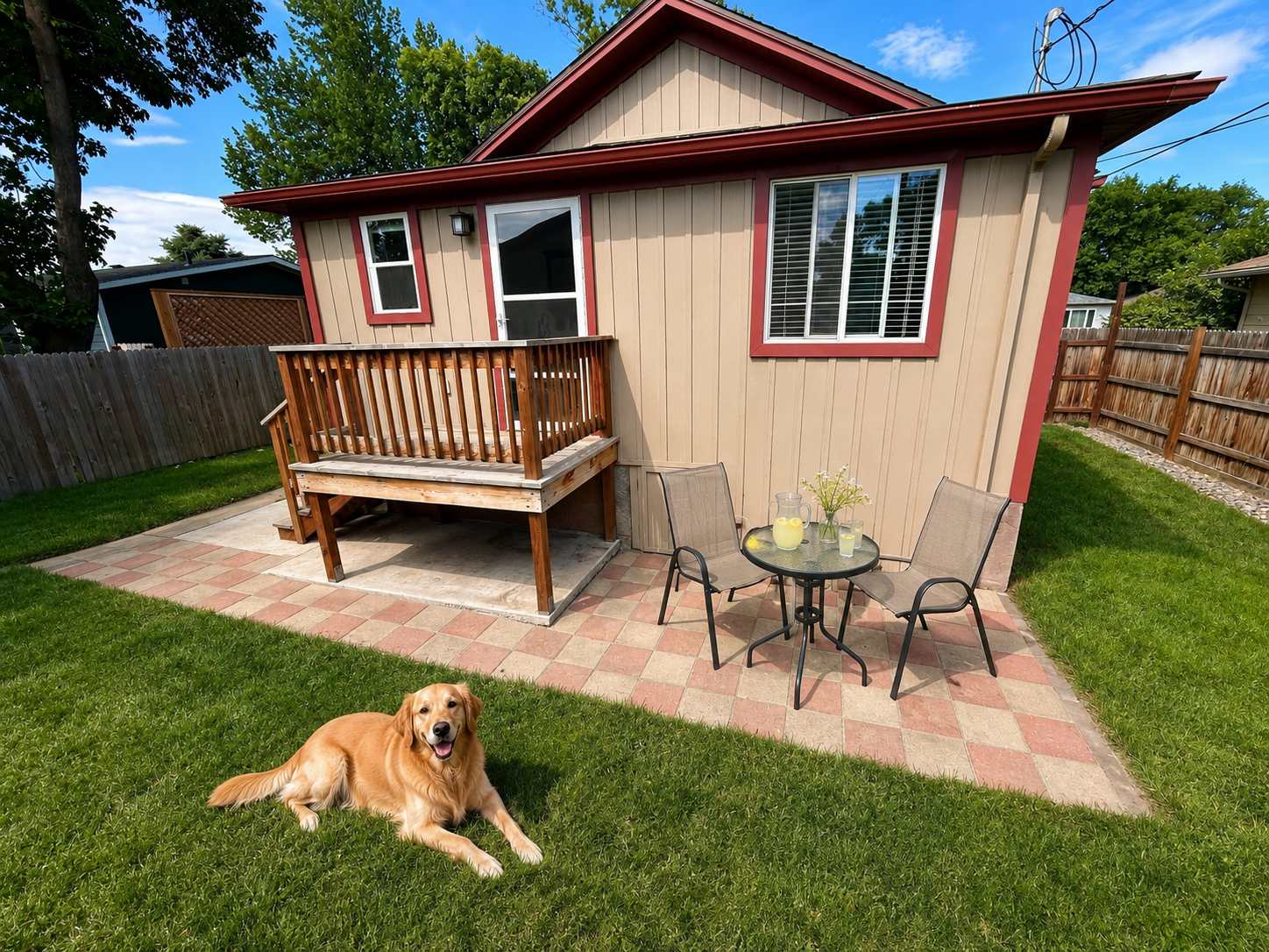 A dog relaxing in The Maple's fully fenced pet-friendly backyard — Sheridan, Wyoming