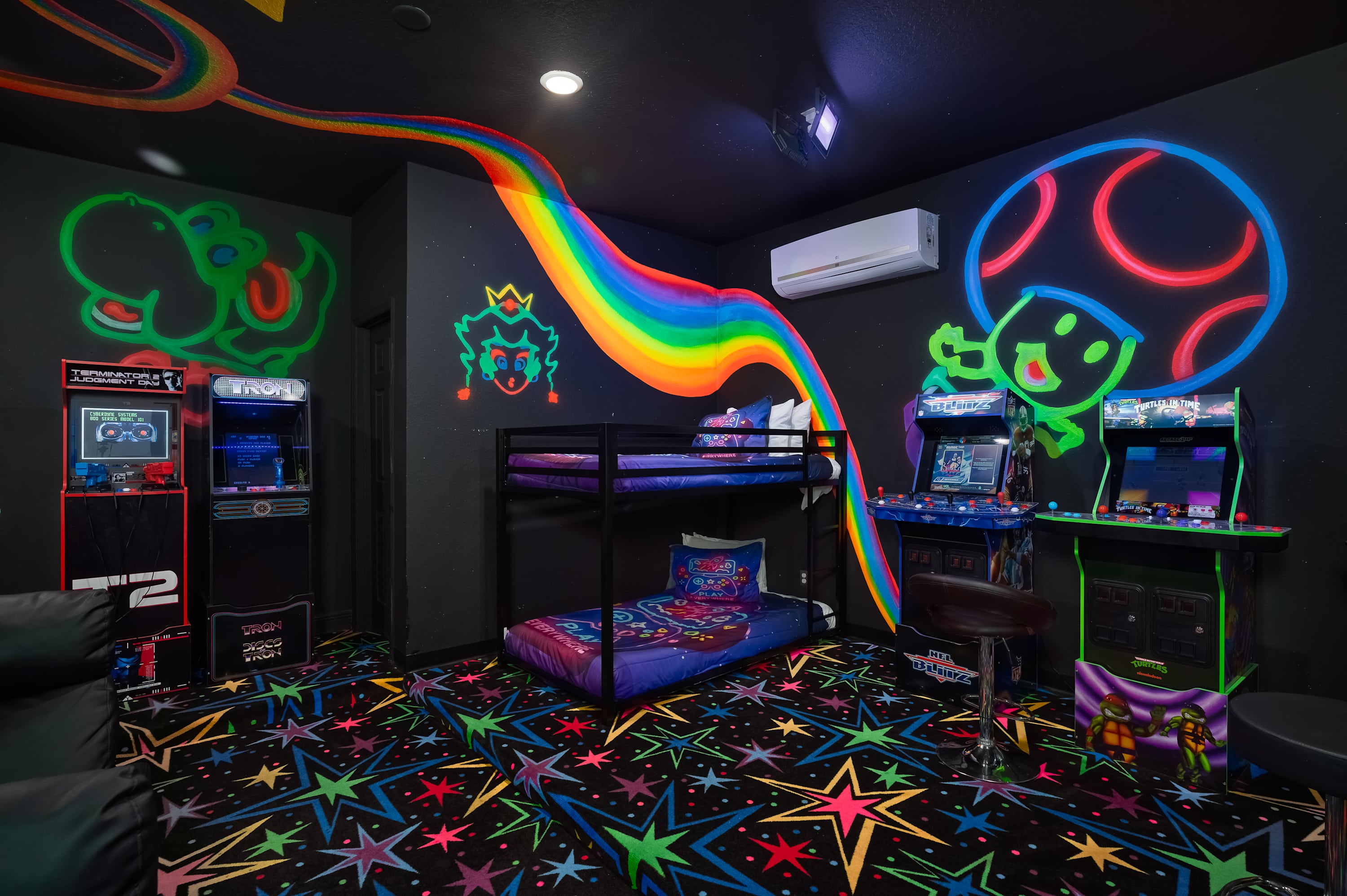 A colorful game room with arcade machines, bunk beds, and vibrant wall murals inspired by classic video games.