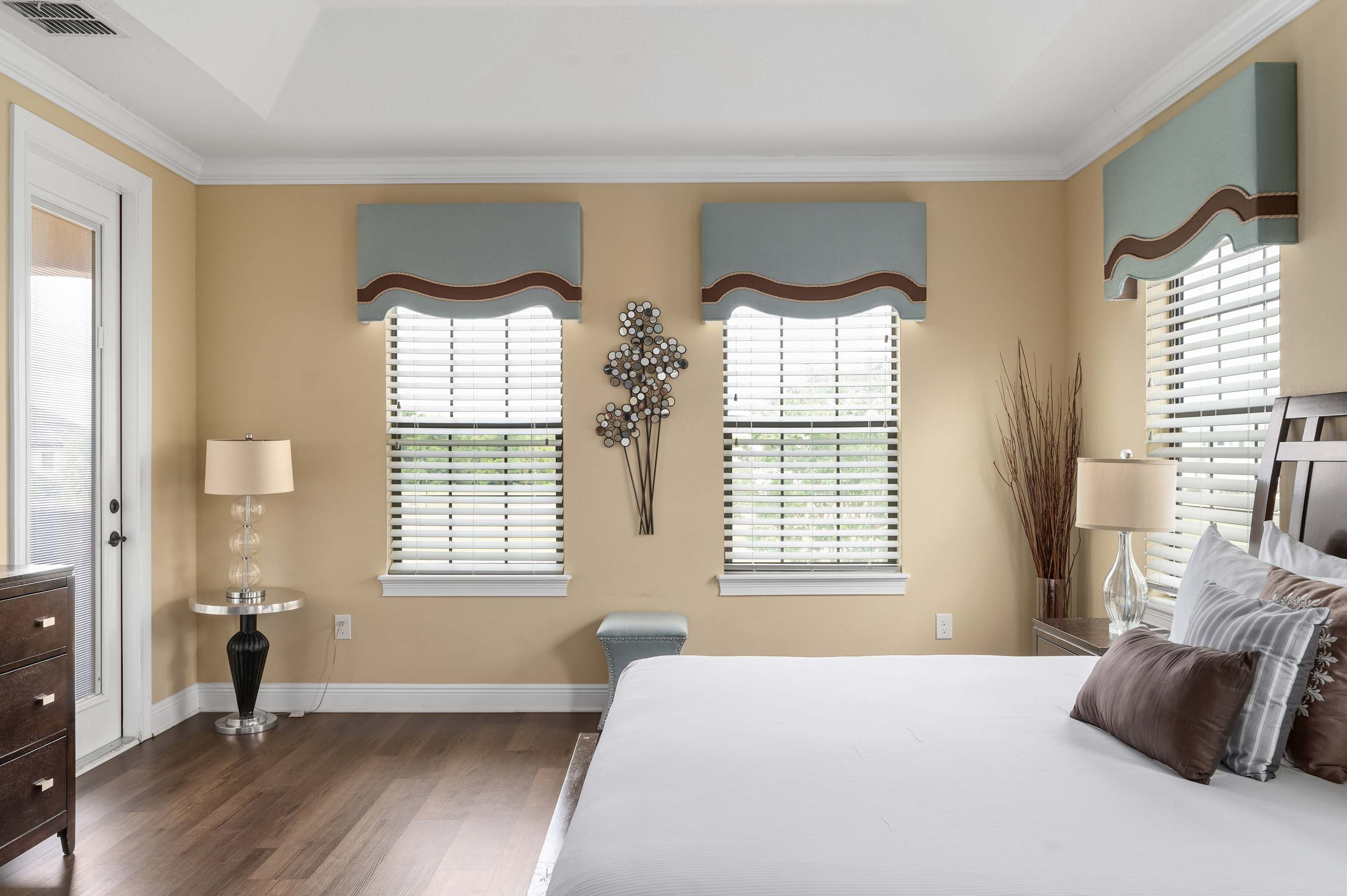 Natural light fills this modern bedroom with soft blue window treatments and wood flooring.