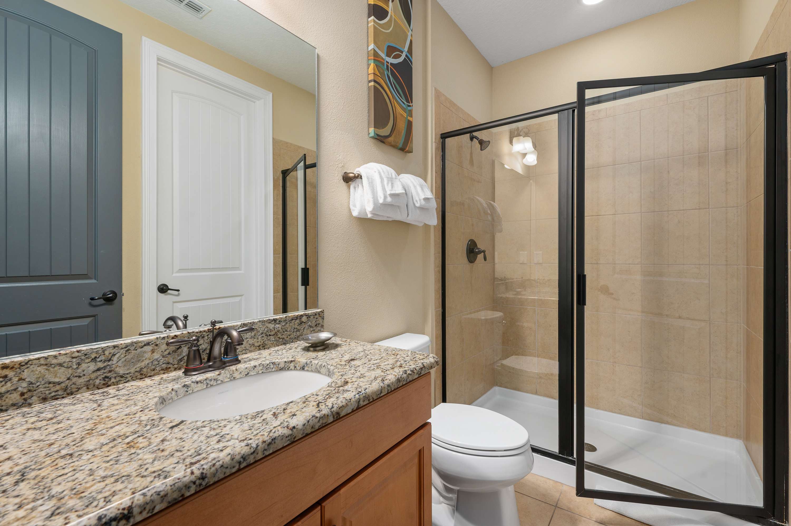 Modern bathroom featuring a granite countertop and glass-enclosed shower.