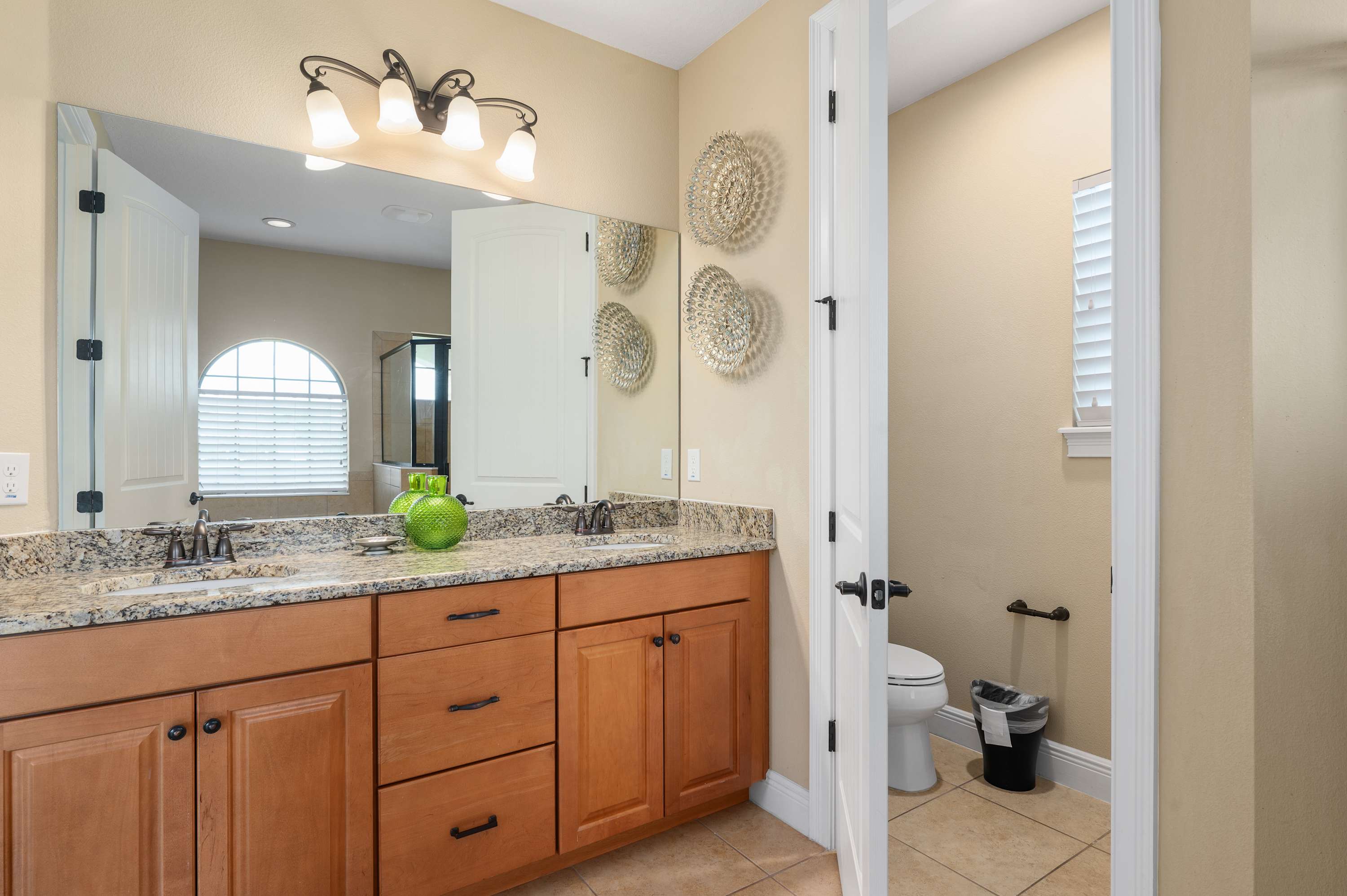 Spacious bathroom with granite countertops and separate toilet area.