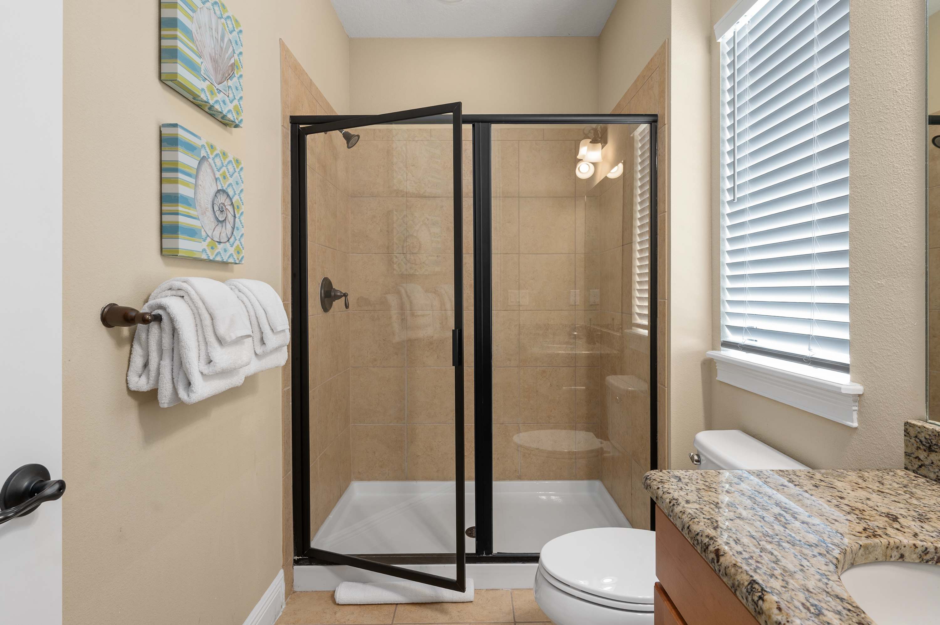 Modern bathroom with a glass-enclosed shower and granite countertop.