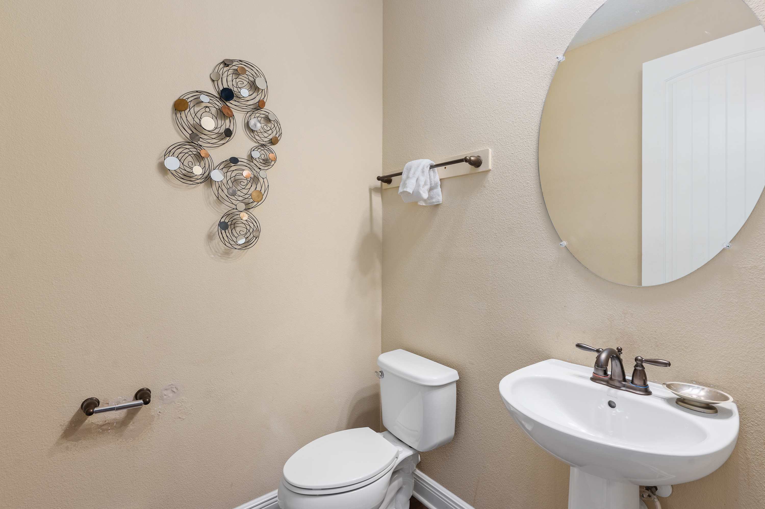 Compact bathroom with a pedestal sink and decorative wall art