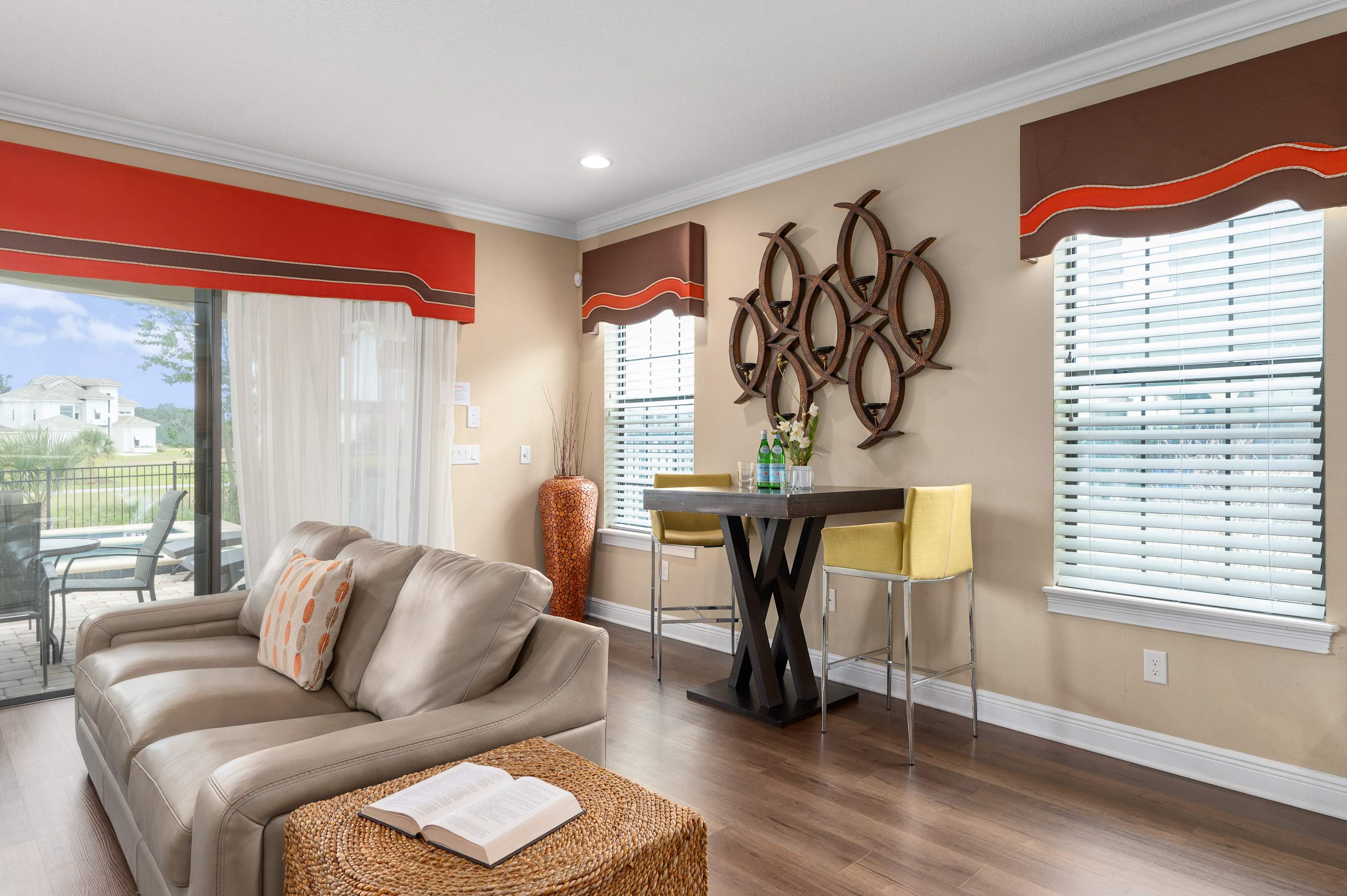 Cozy living area with leather seating and a high-top dining table near bright windows.