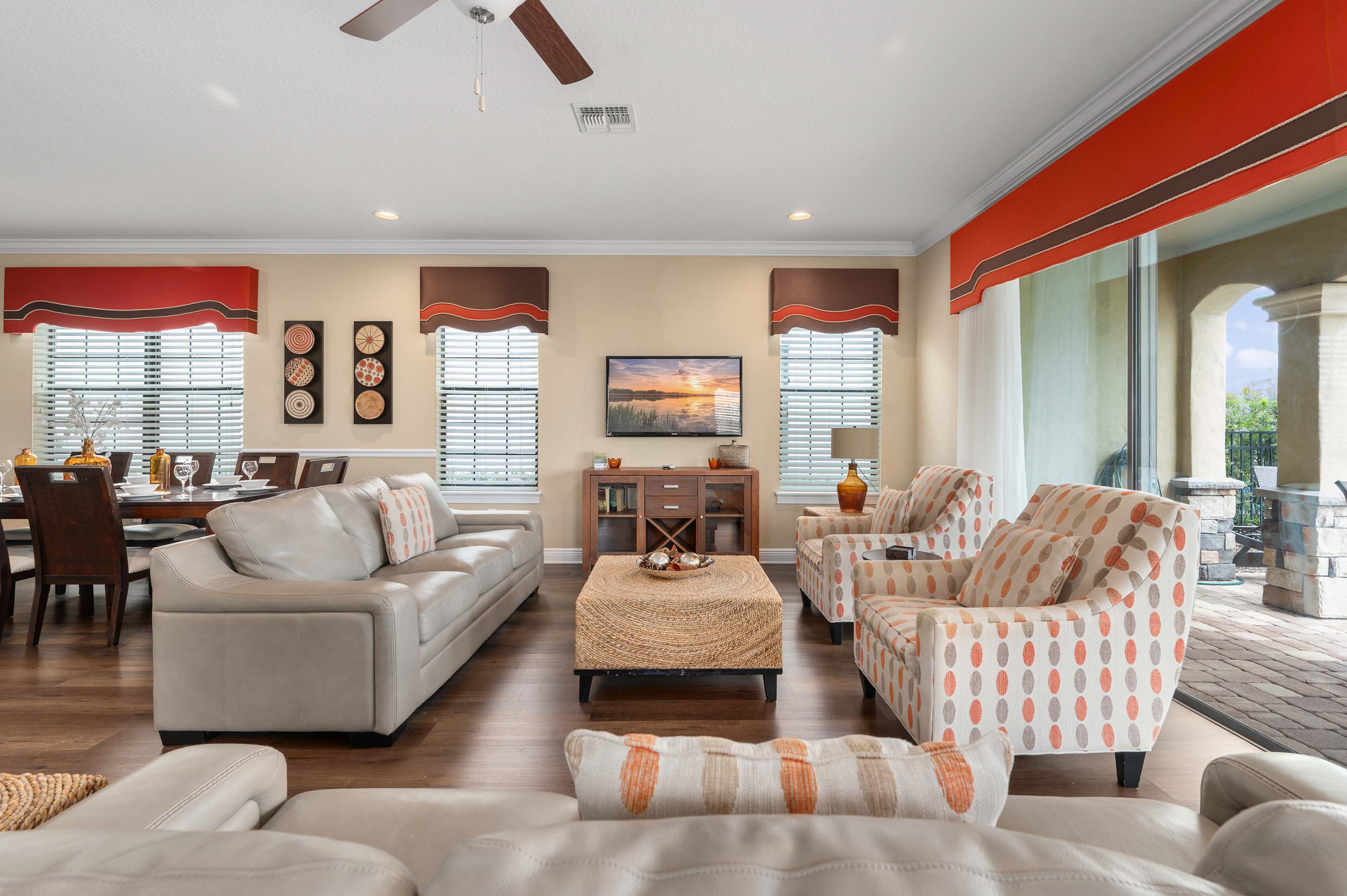 Spacious living room with patterned armchairs and sliding glass doors leading to a covered patio.