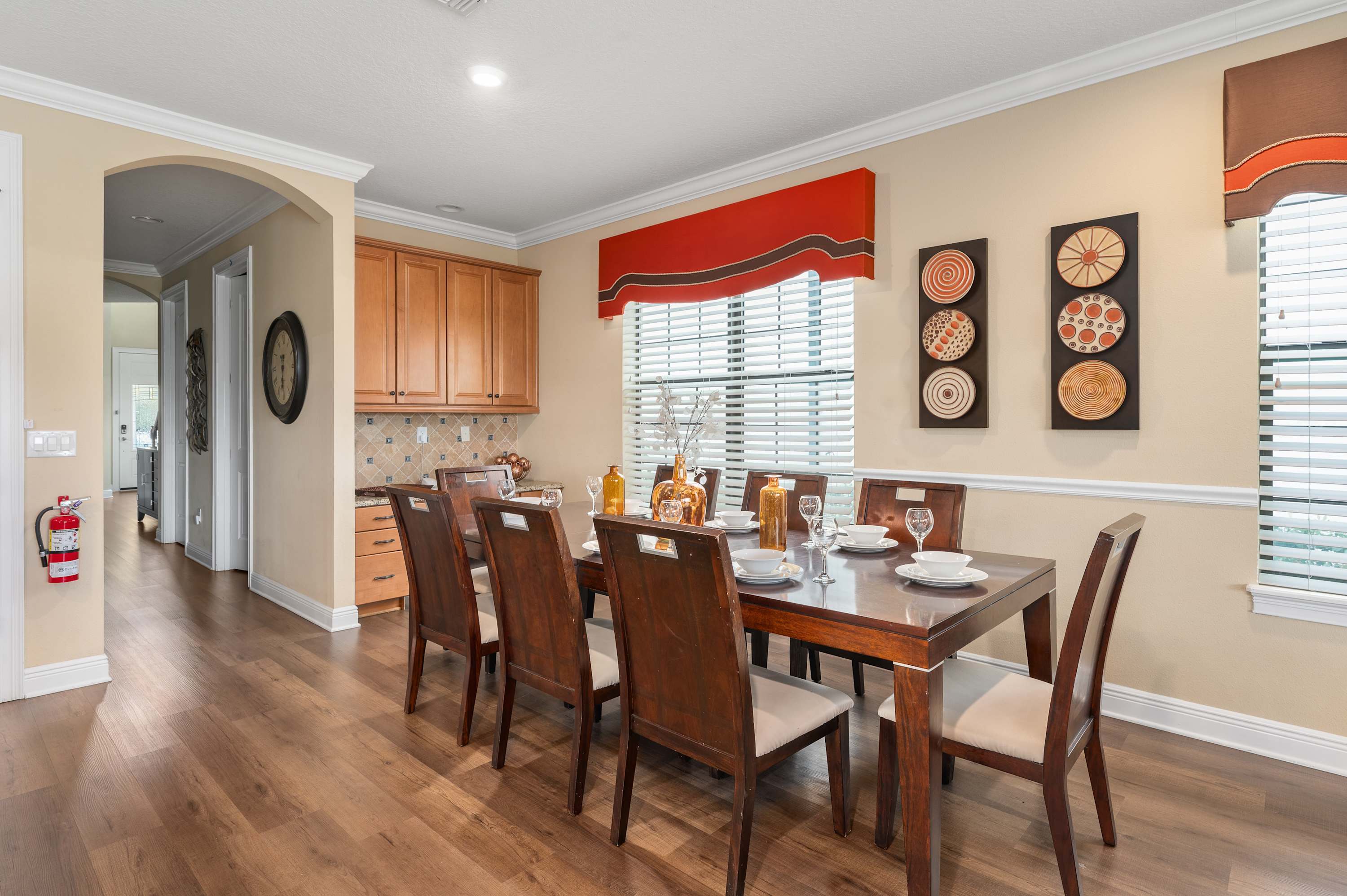 Dining area with a wooden table set for six and natural light from large windows