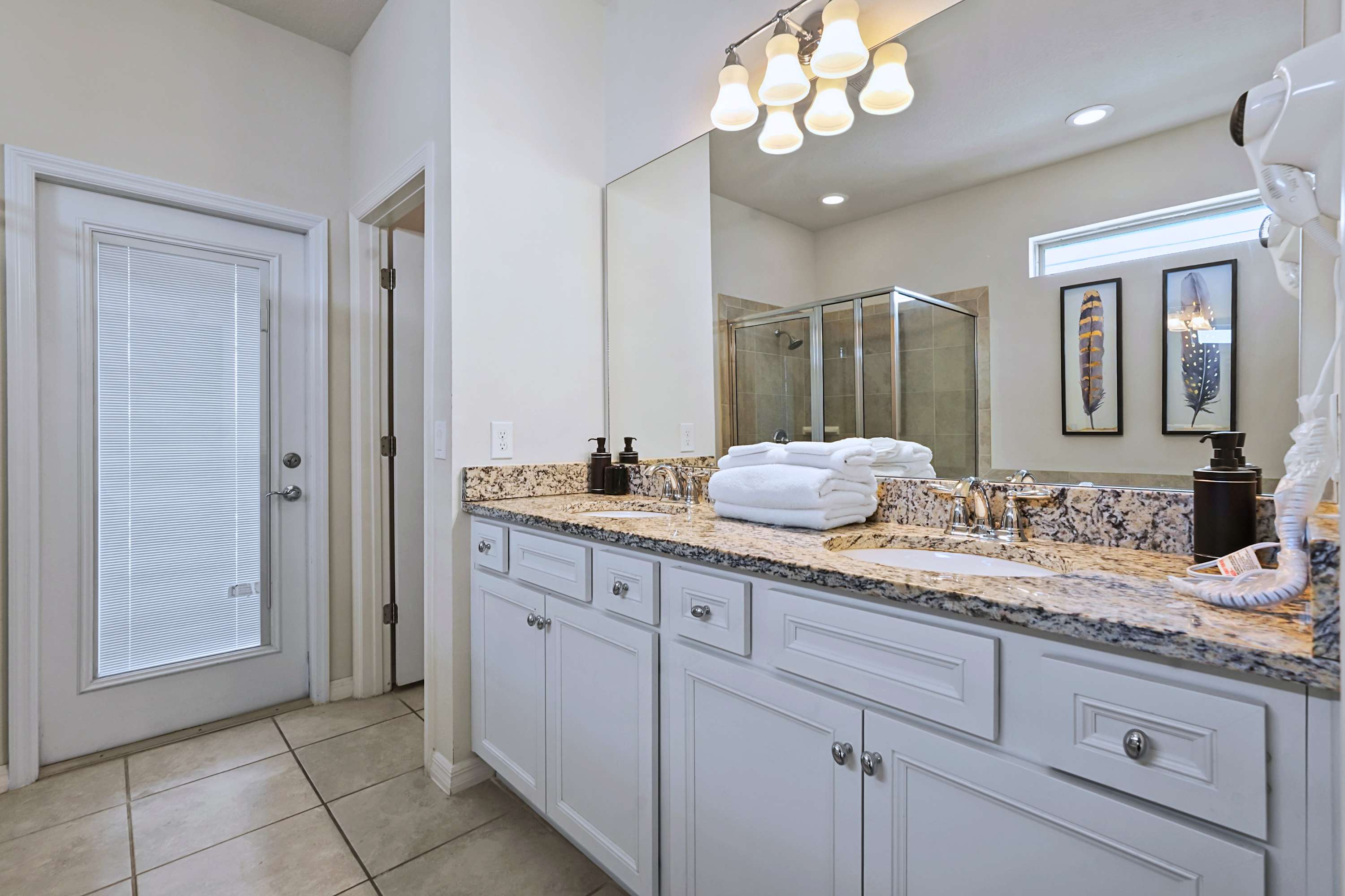 Bright, pristine full bathroom featuring premium granite counters and direct patio access.