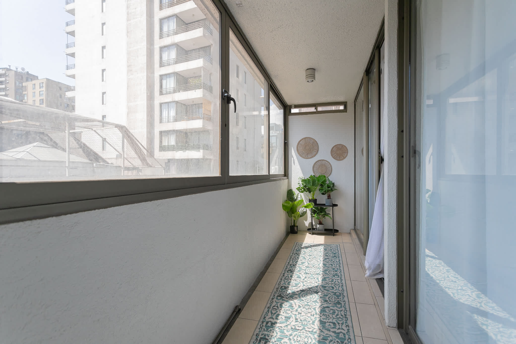 Bright and cozy enclosed balcony with lush plants and decorative touches, perfect for relaxation.
