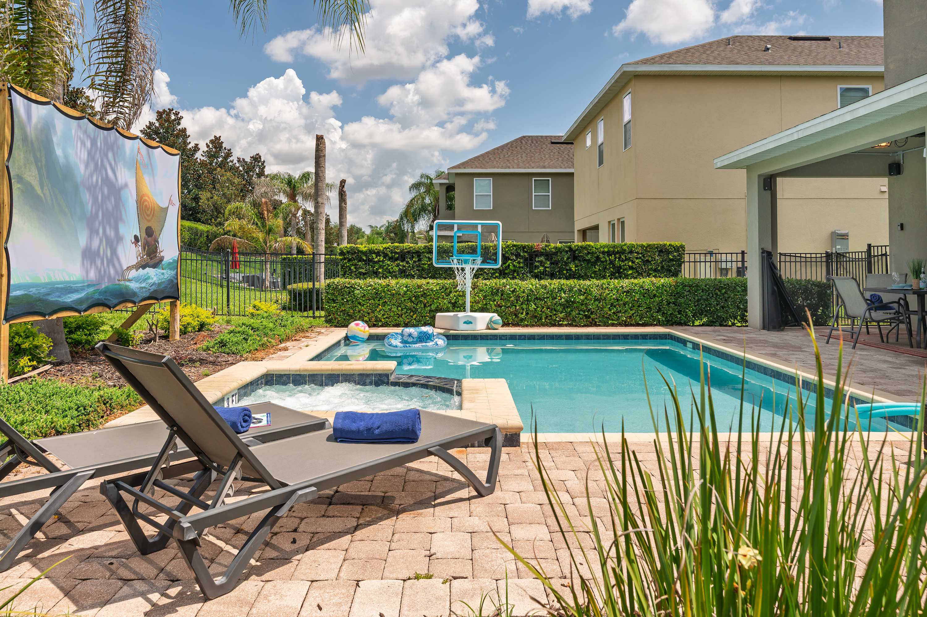 Relax by the pool with a hot tub and basketball hoop in a sunny backyard setting.