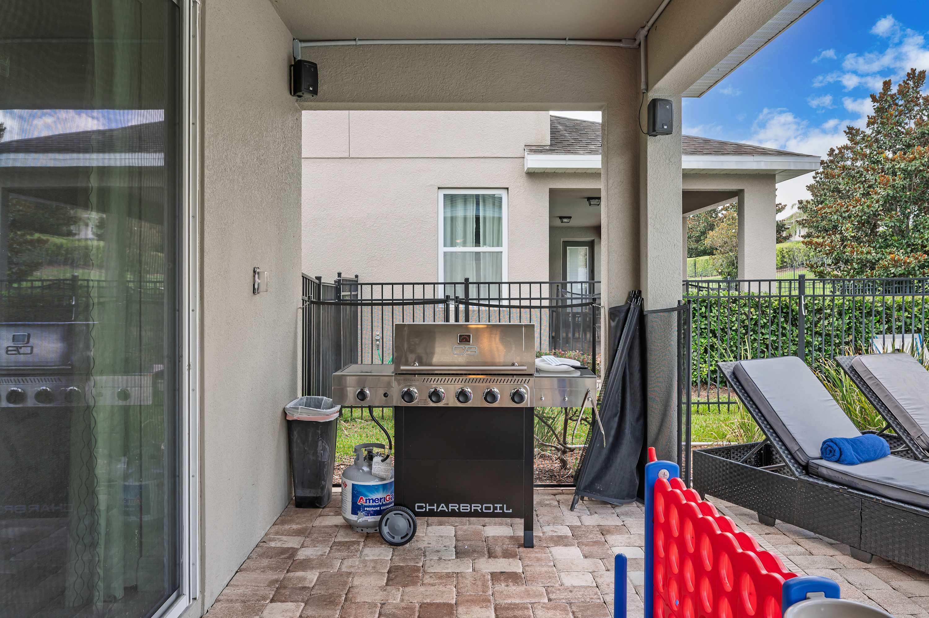 Covered patio with a stainless steel grill and outdoor seating for relaxing.