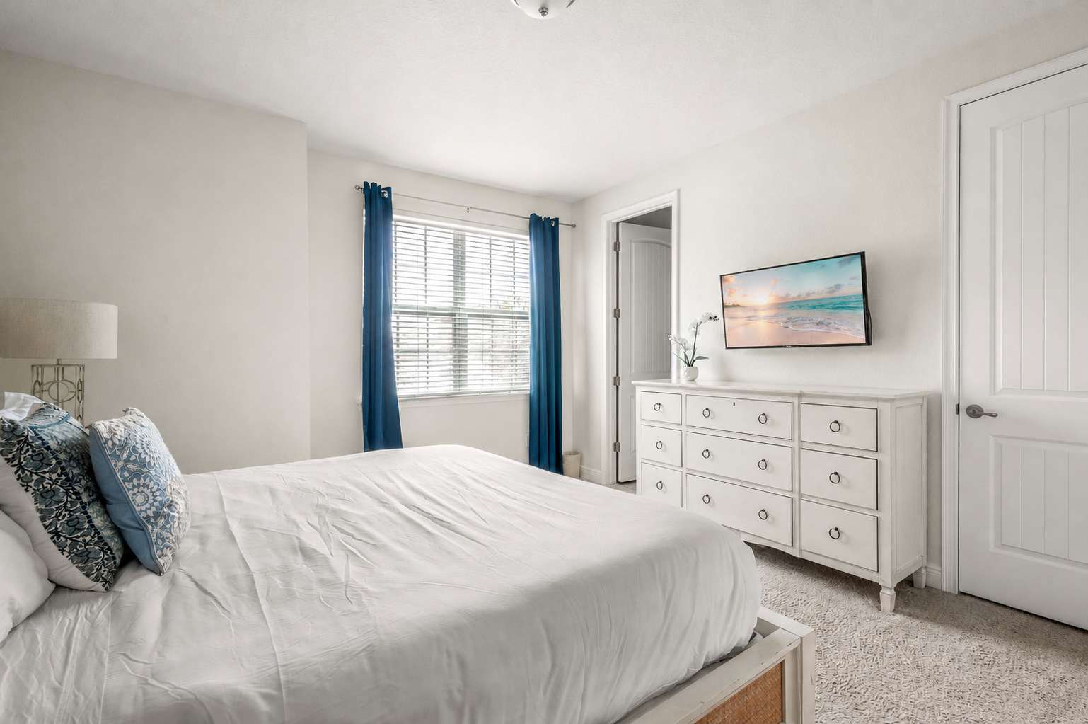 Bright bedroom with a white dresser and wall-mounted television