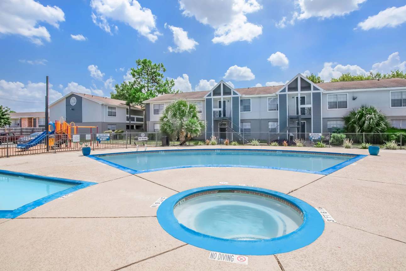 Relax in the inviting pool area with a hot tub and playground, perfect for family fun under sunny skies. (Common Area)