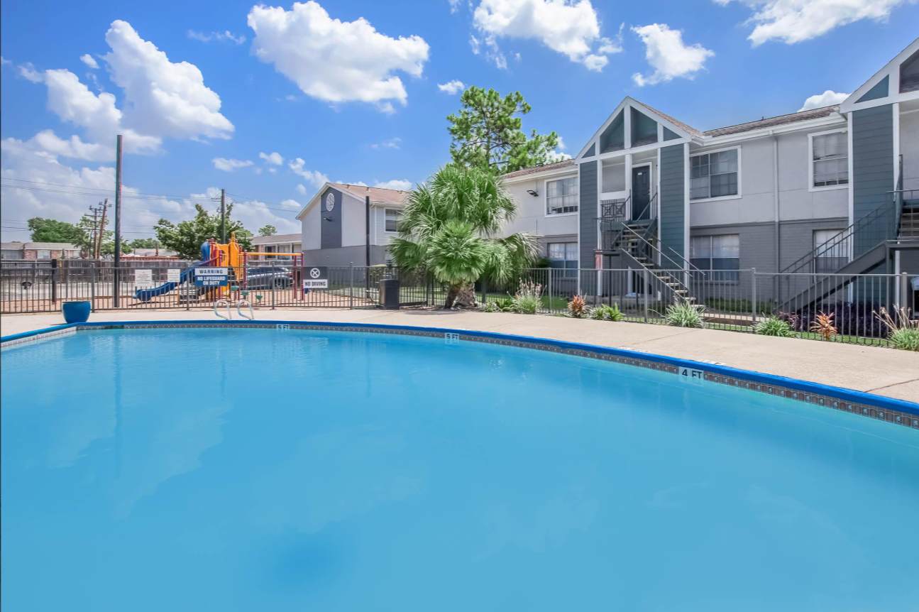 Enjoy a refreshing swim in this inviting pool, surrounded by lush greenery and sunny skies.