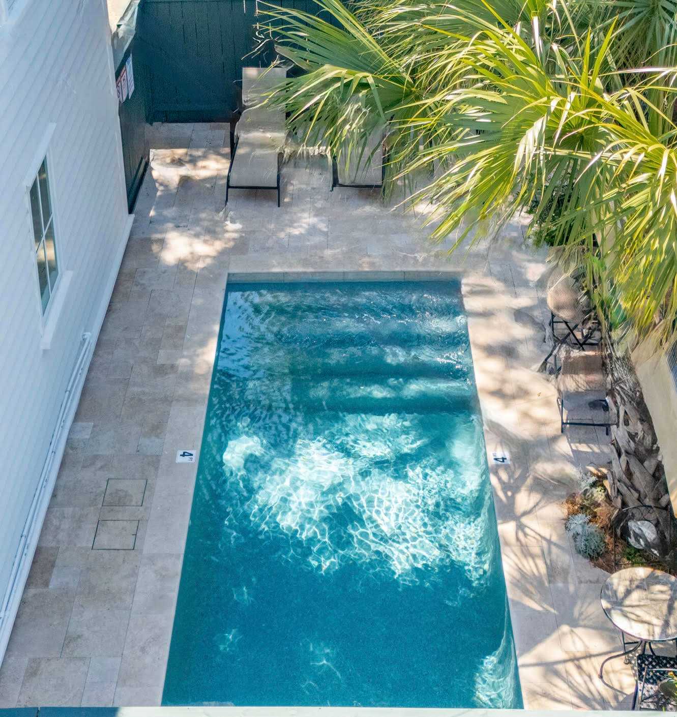 An aerial view of a small pool with a palm tree and furniture nearby.