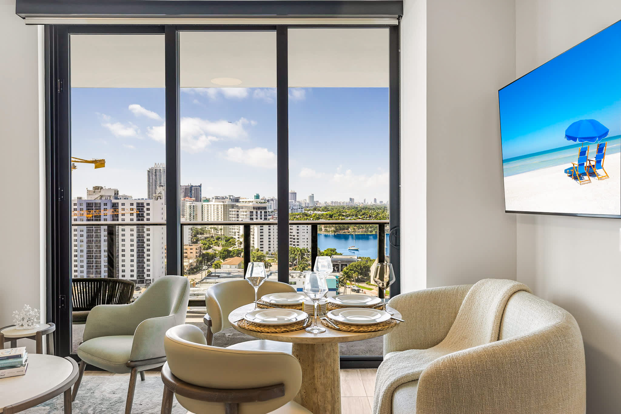 Elegant living and dining area with floor-to-ceiling windows showcasing panoramic city and waterfront views.