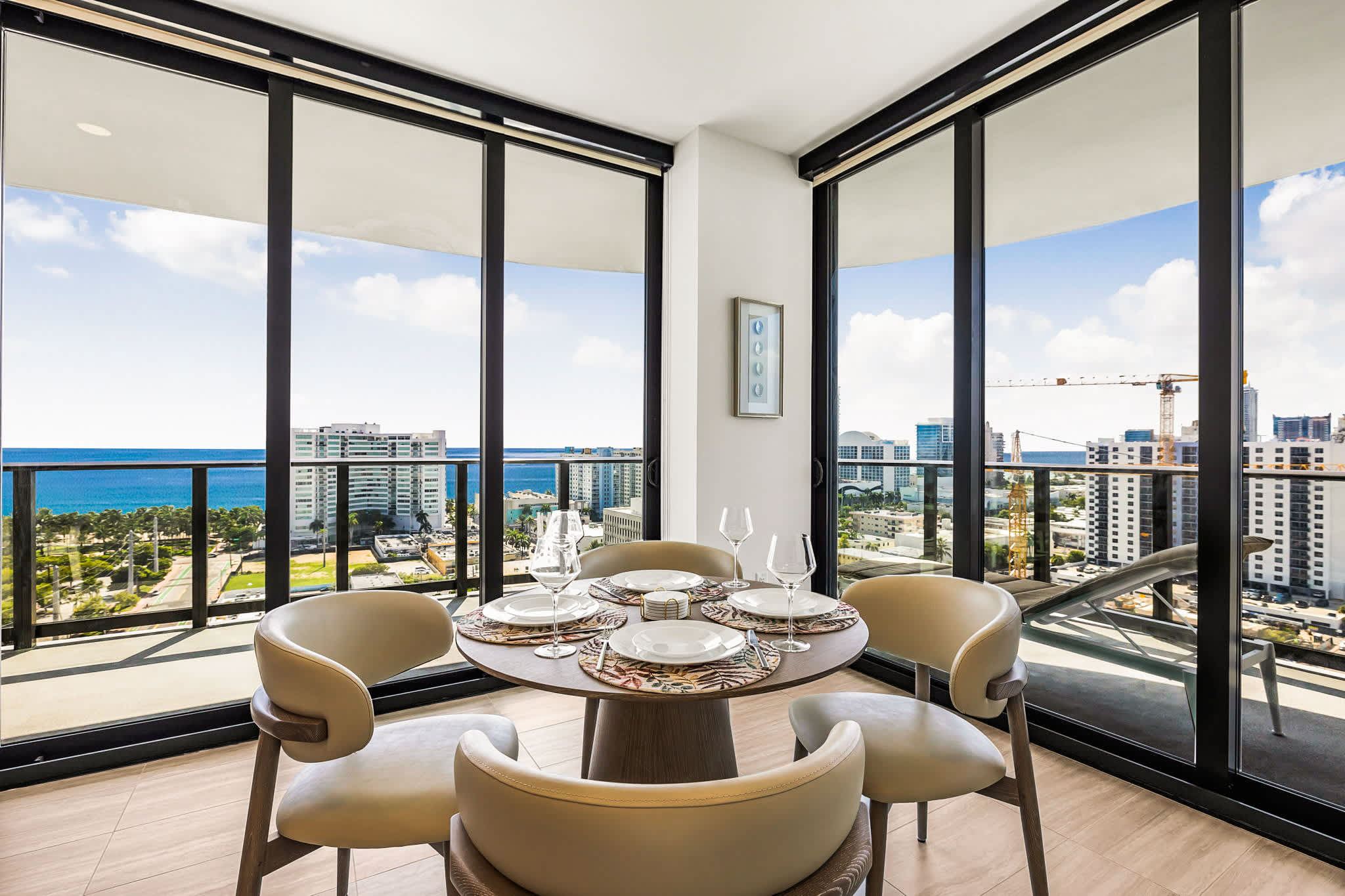 Enjoy meals at a beautifully set dining table surrounded by floor-to-ceiling windows and sweeping ocean and city views.