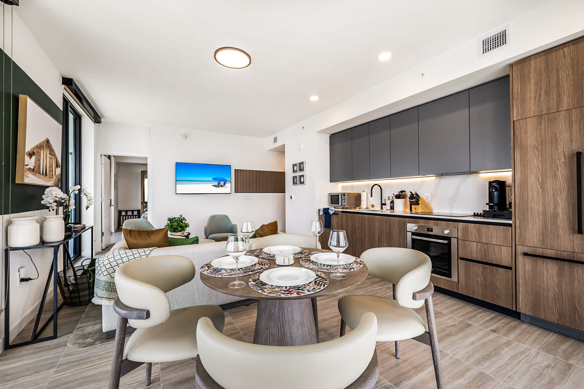Open-plan kitchen and dining area with seating for six, sleek wood cabinetry, and a fully set table for shared meals.