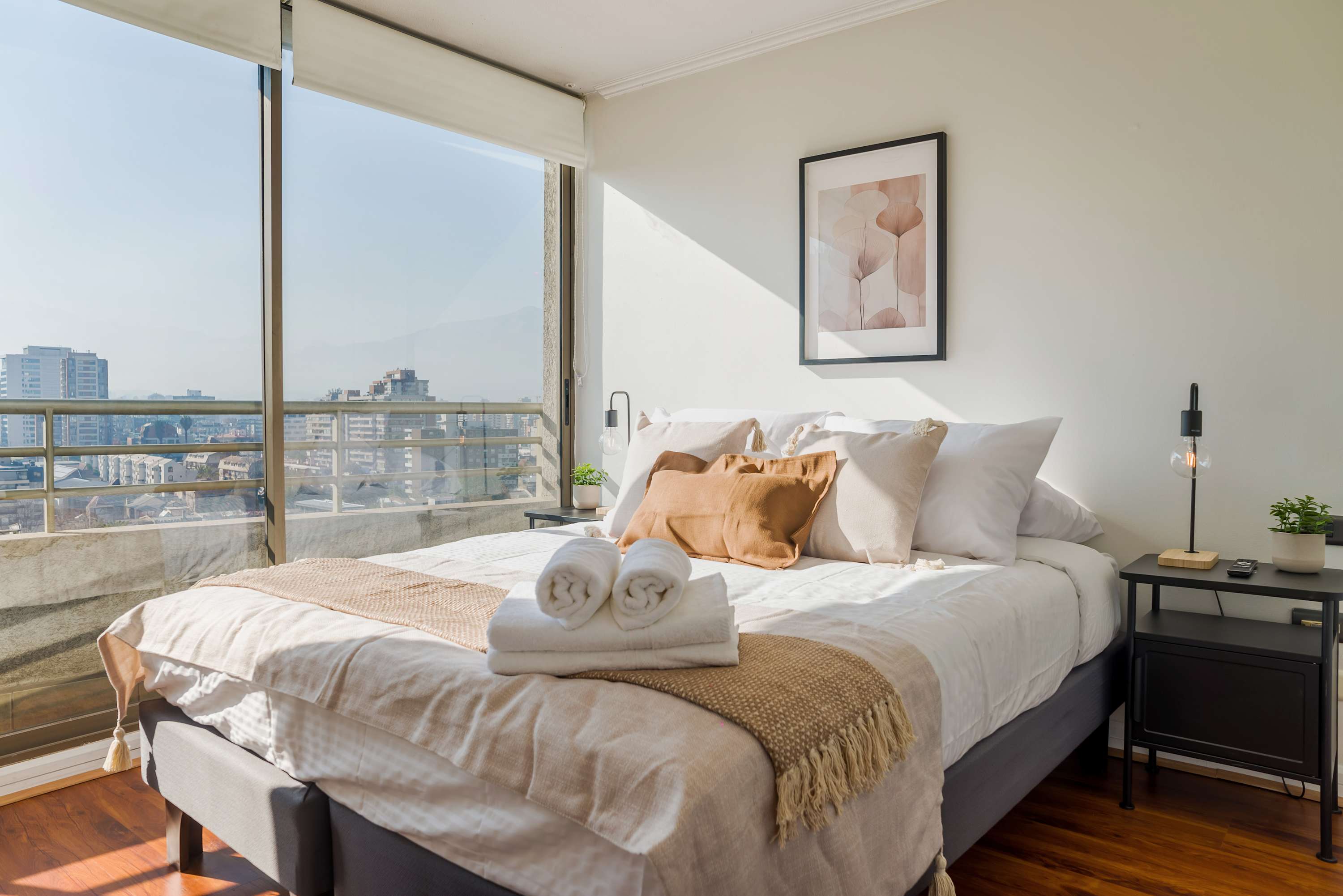 Relax in a sunlit bedroom with stunning city views, plush bedding, and modern decor.