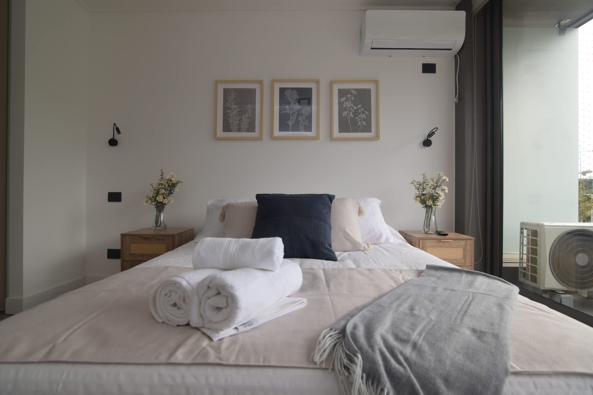 Relax in this cozy bedroom with modern decor, plush bedding, and natural light from large windows.