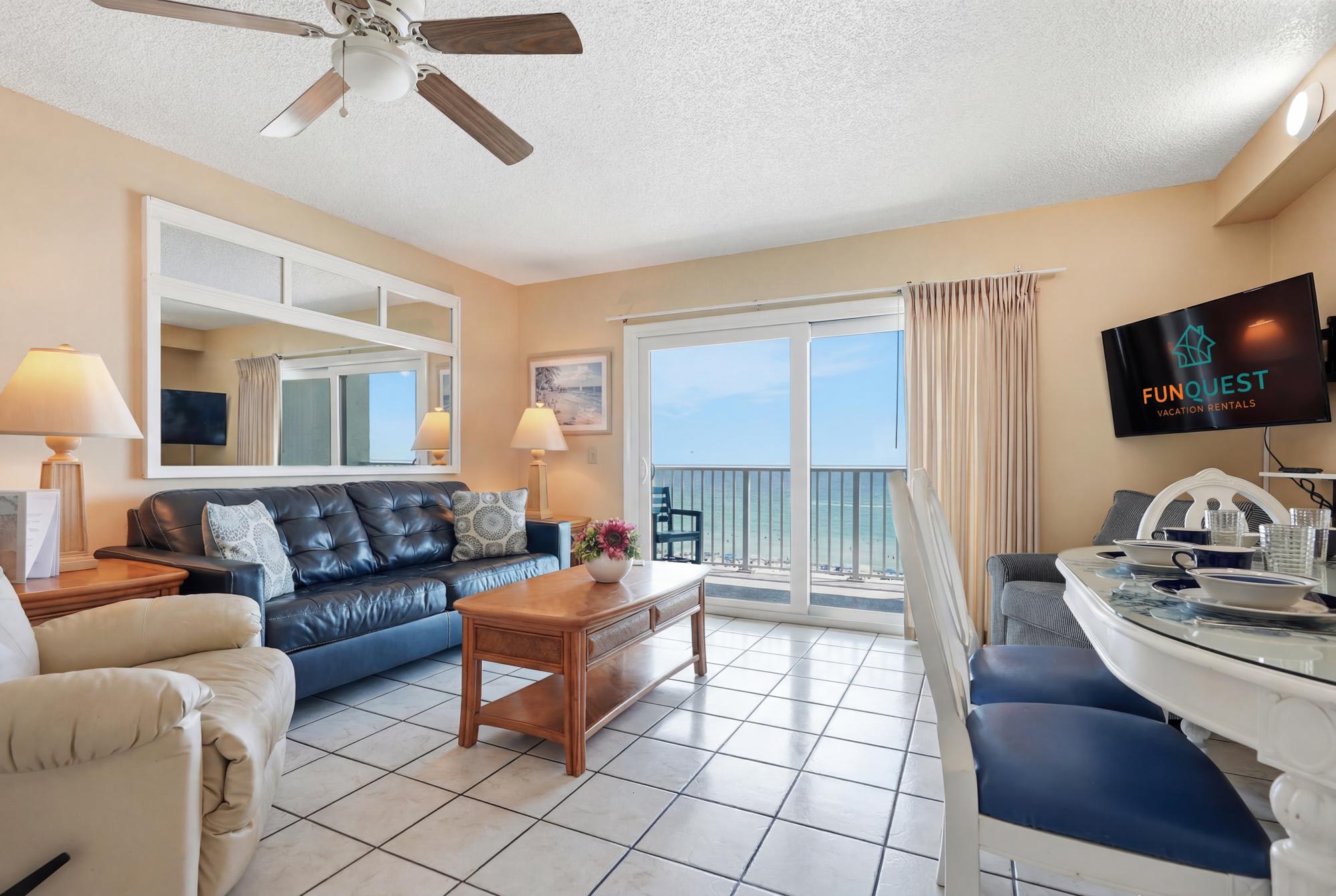The Summit 830 – Living room with ocean view, leather couch, dining table, and sliding glass doors.