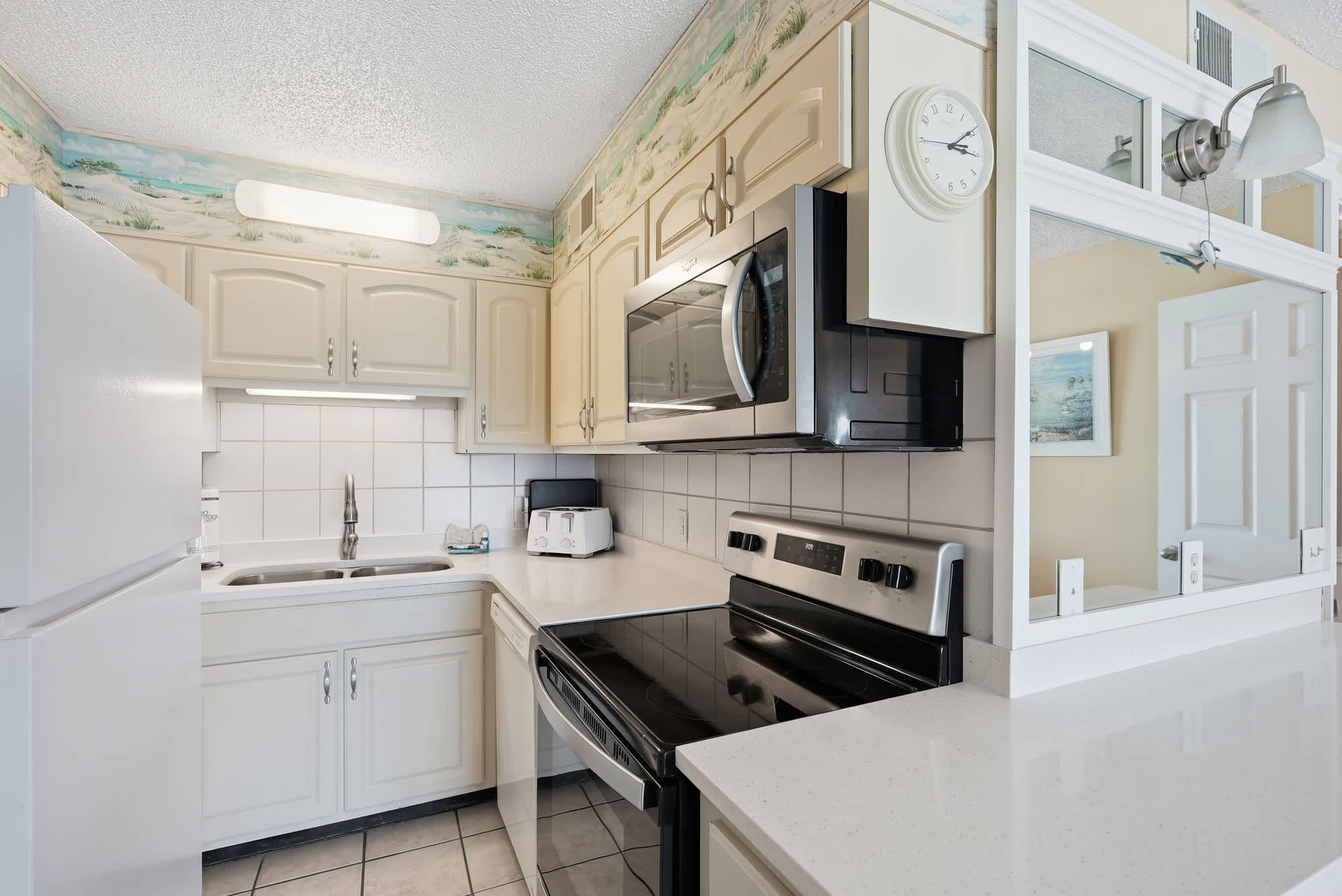 The Summit 830 – Kitchen with white cabinets, stainless steel appliances, and a window above the sink.