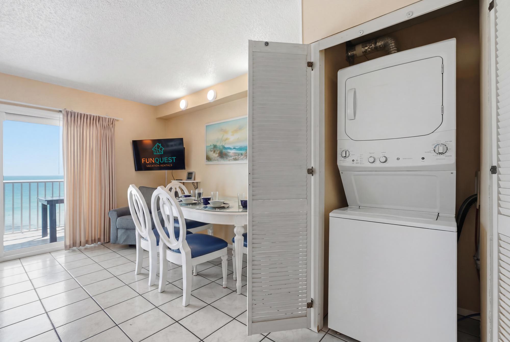 The Summit 830 – Bright living area with dining table, TV, ocean view, and stacked washer-dryer in closet.