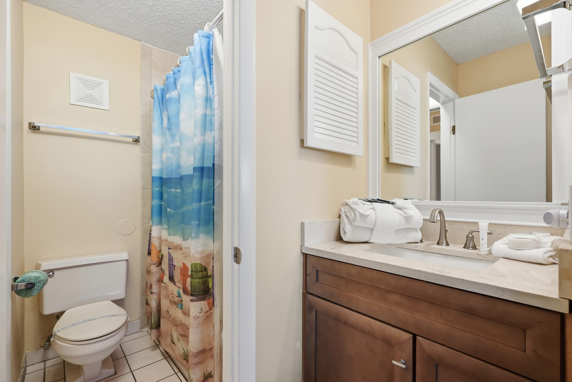 The Summit 830 – Compact bathroom with a shower, toilet, sink, and beach-themed shower curtain.