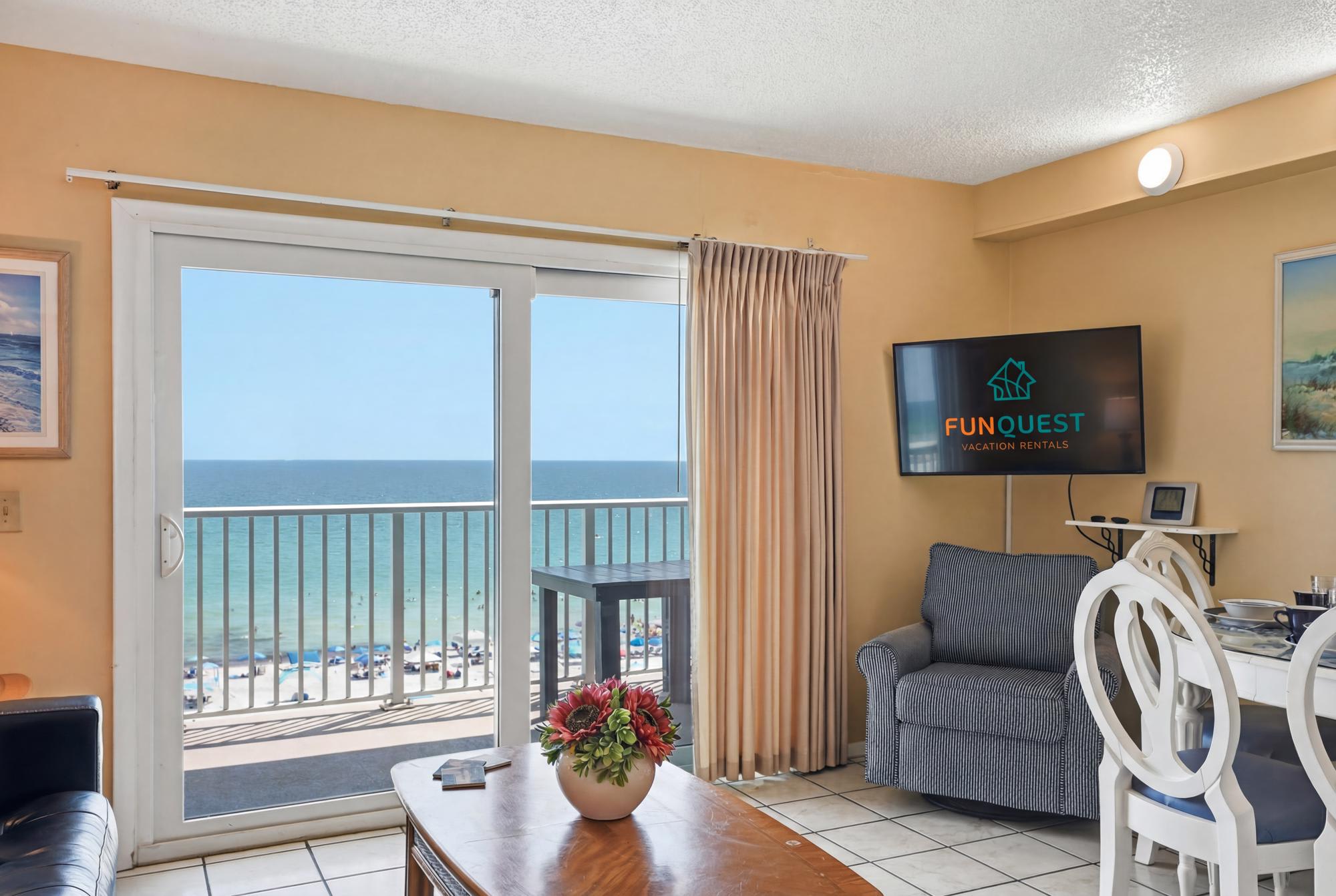 The Summit 830 – Coastal view from a living area with a sofa, dining table, and large sliding glass door.