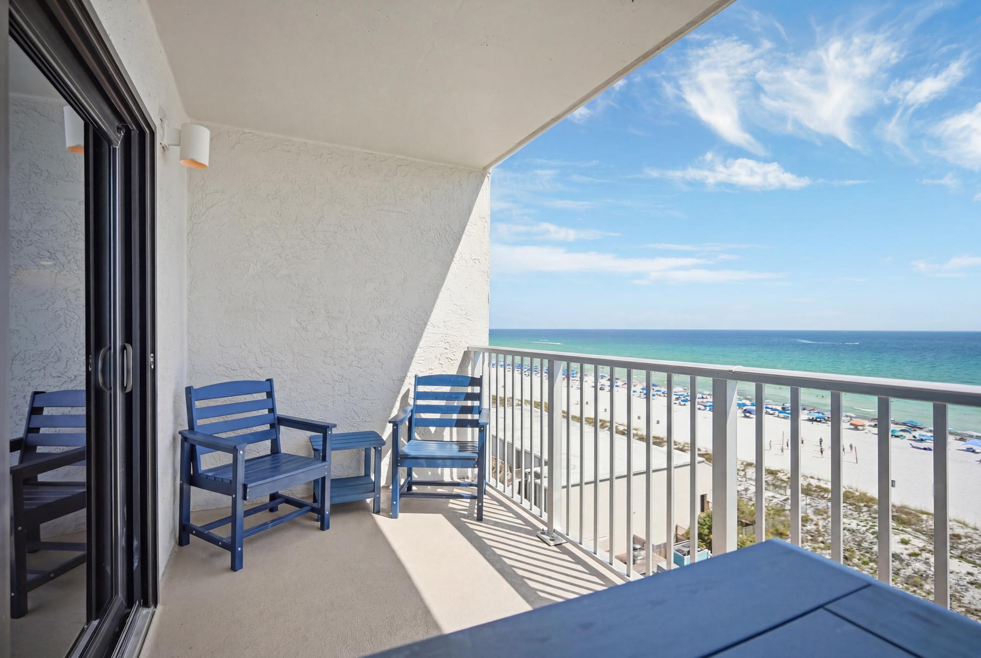 The Summit 830 – Balcony with blue chairs, ocean view, and sandy beach below.