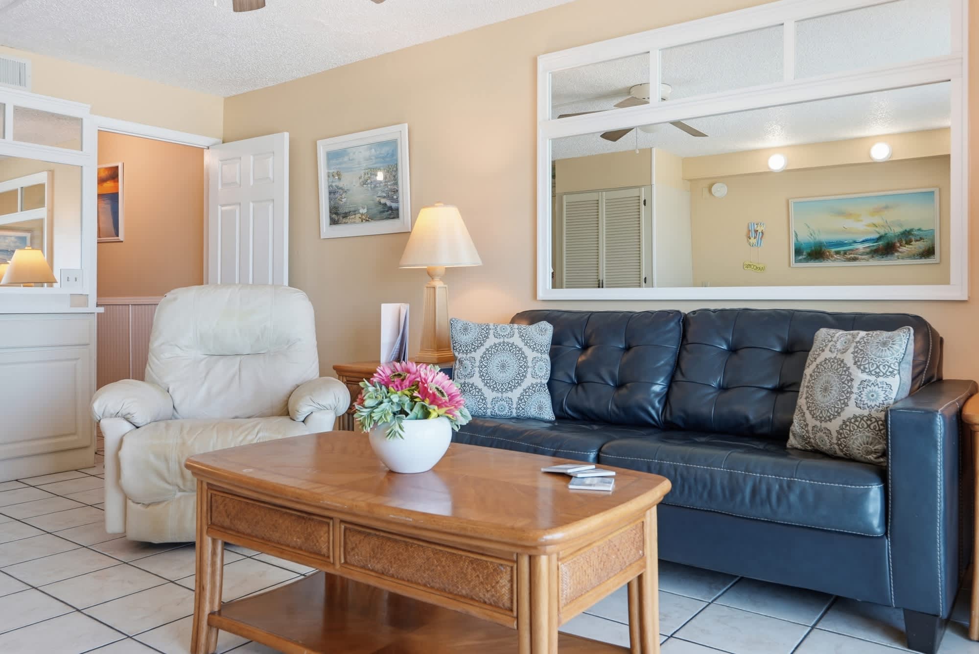 The Summit 830 – Living room with leather couch, armchair, coffee table, and decorative artwork on beige walls.