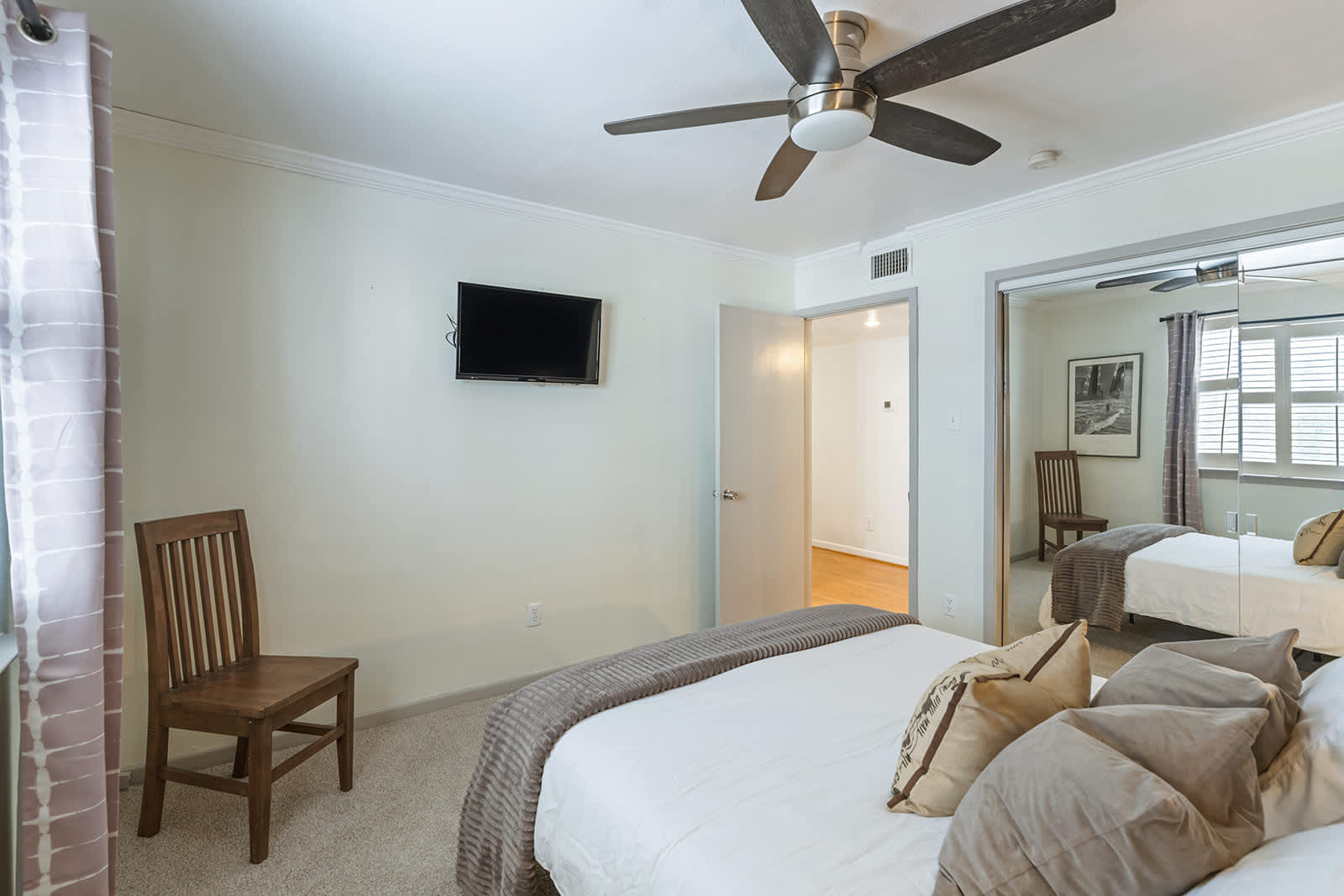 Relax in this cozy bedroom with a comfy bed, modern ceiling fan, and convenient wall-mounted TV.