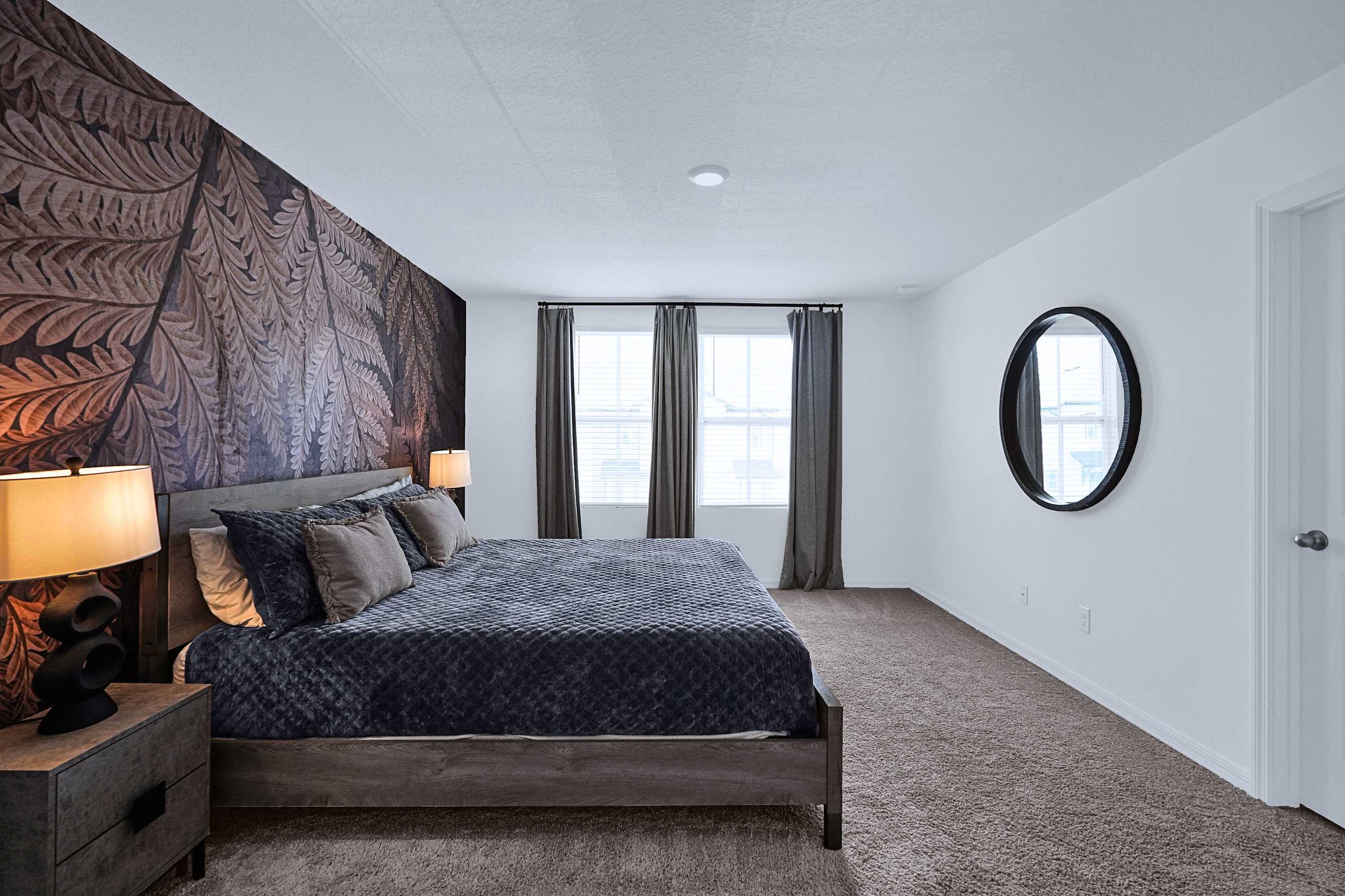 Well designed bedroom with a luxurious king bed, warm lighting, and modern mirror
